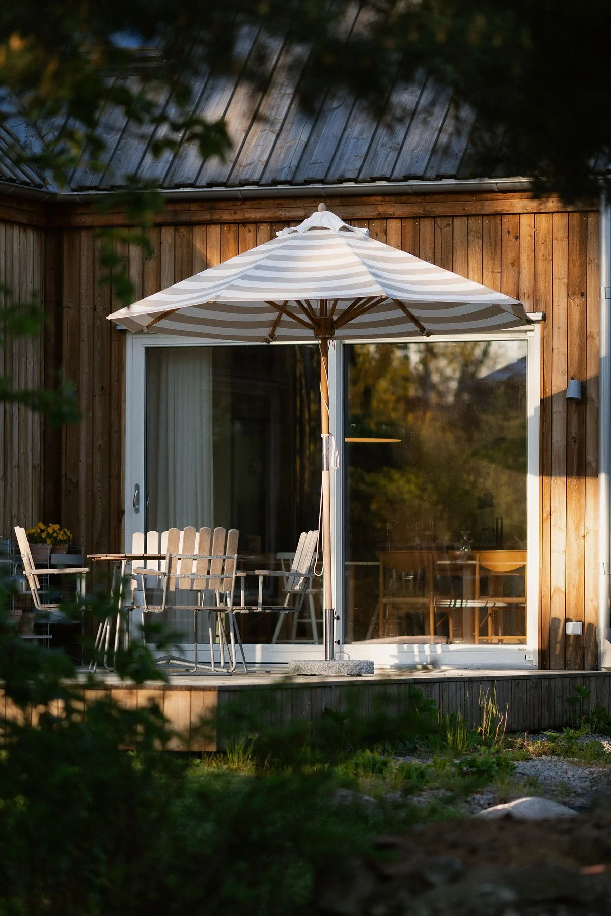 Le parasol Hisshult de 1898 se trouve devant la maison en bois et sur la terrasse de @applauden, à côté d'un groupe de sièges de Grythyttan.