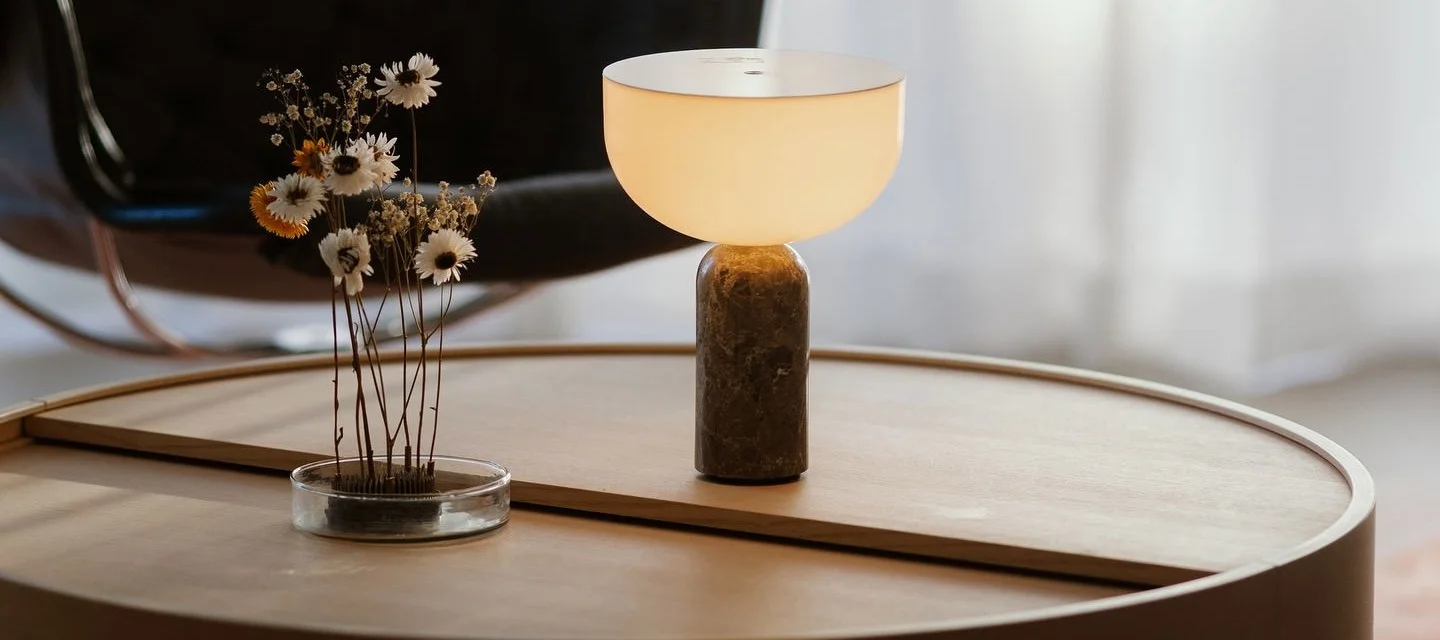 La table basse Arc de Woud est décorée d'une lampe de table Kizu de New Works et d'un hérisson à fleurs Garden Glory.