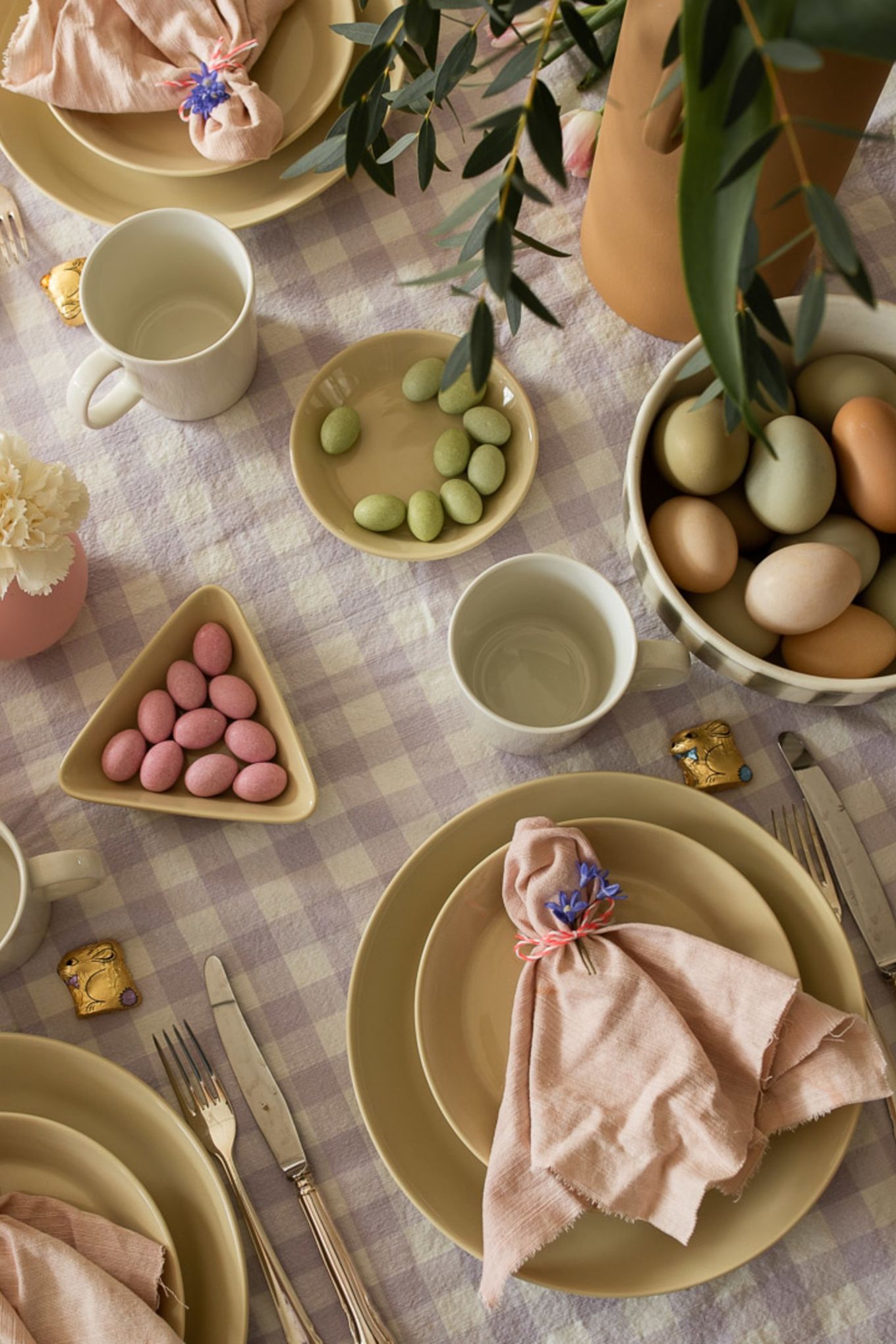 Les idées de décoration de table pour Pâques incluent toujours un joli pliage de serviette, comme vous le voyez ici avec un simple pliage et une fleur enroulée autour d'une serviette en lin Scandi Living de couleur rose. 