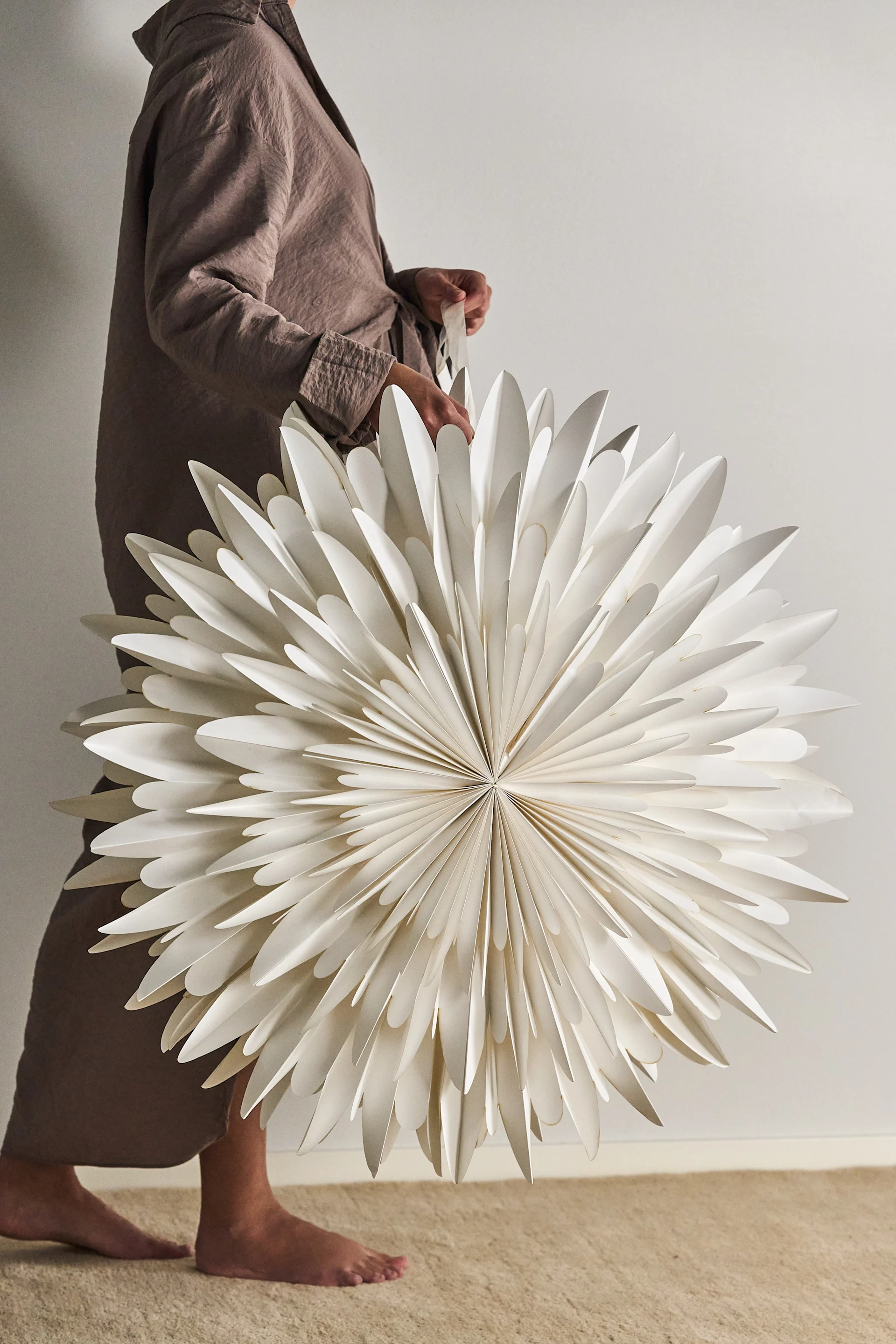 Une femme tient une grande étoile de Noël scandinave dans les mains.