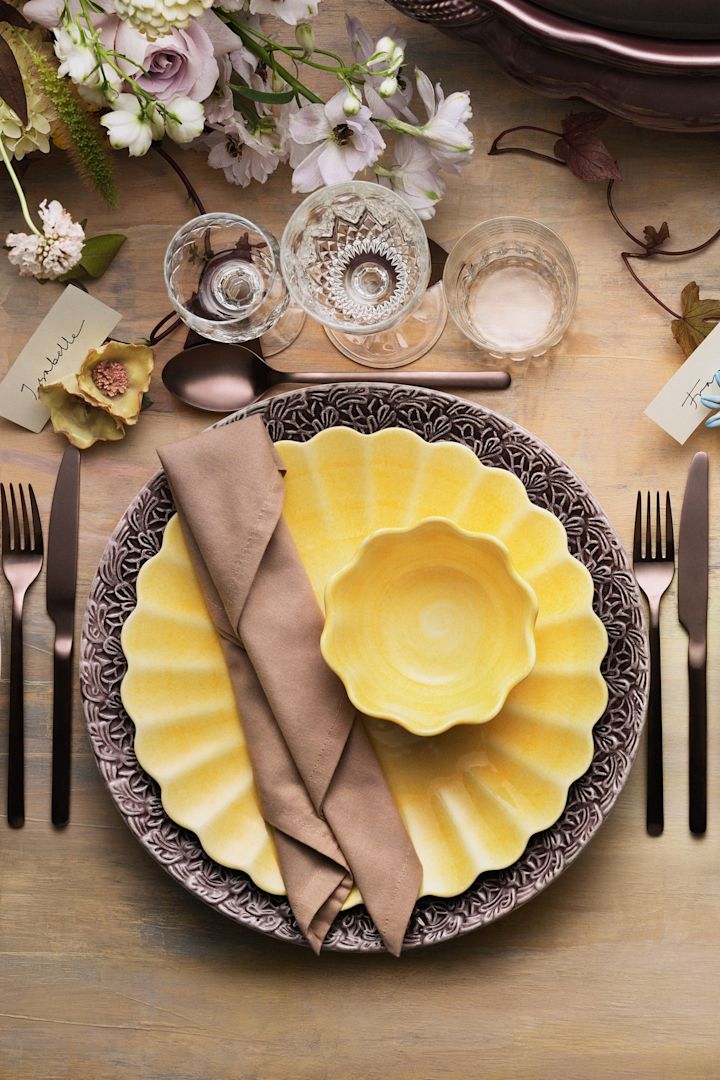 Une table dressée avec de la vaisselle jaune de la collection Oyster de Mateus.