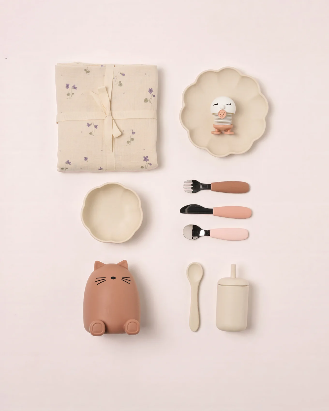Set bébé: couverture fleurie, assiette festonnée avec oiseau jouet, bol, récipient chat, couverts, cuillère et tasse à couvercle.