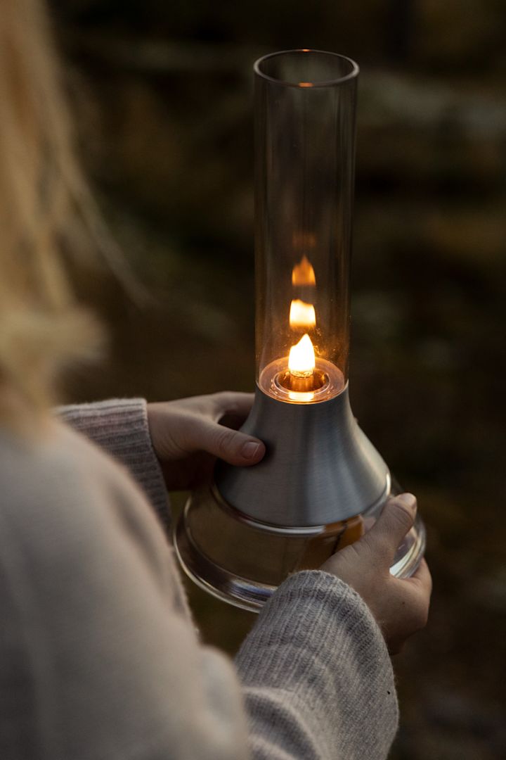 Le lagom au fil des saisons : une femme tient à la main la lampe à pétrole Fyr de Design House Stockholm.