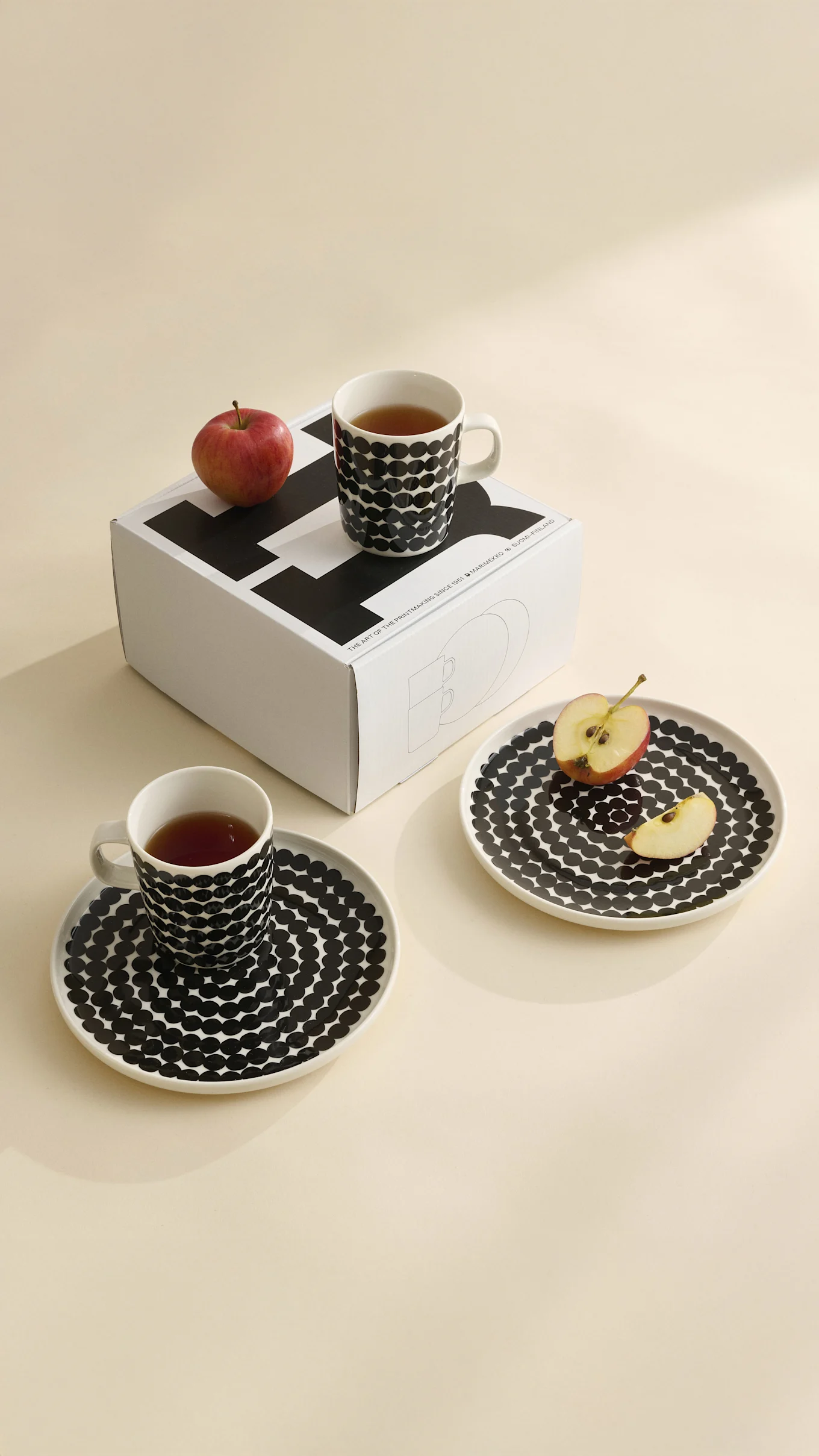 Six tasses avec motifs floraux, à pois et graphiques en noir, blanc, beige. Une fleur orange dans l'une.