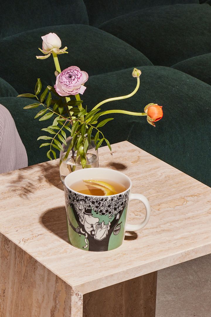 La tasse verte de Moomin est posée sur une table basse avec du café.