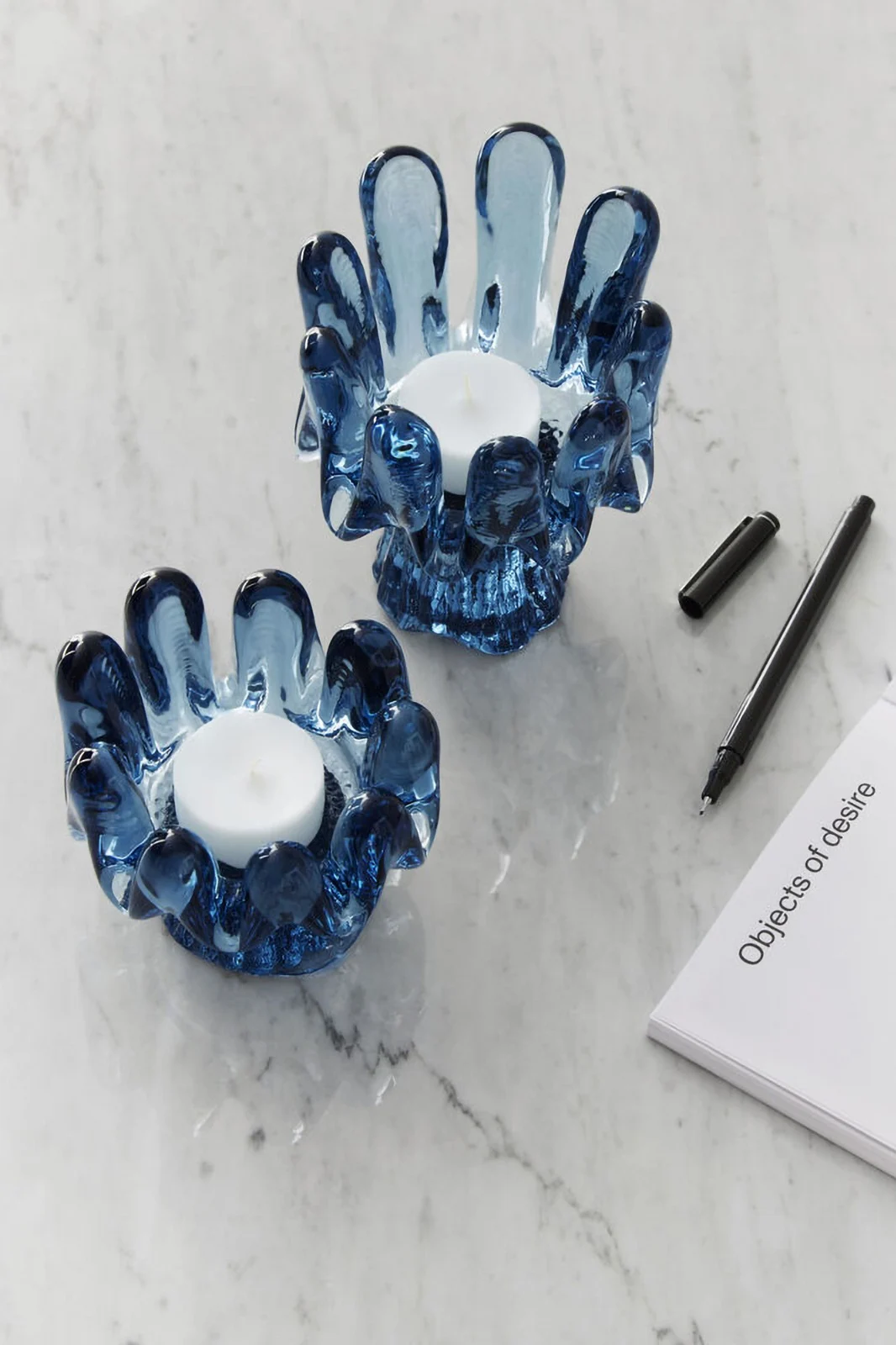 Tendances de la décoration intérieure 2025 : Deux bougeoirs bleus de la collection Solros de Kosta Boda sont posés sur une table claire.