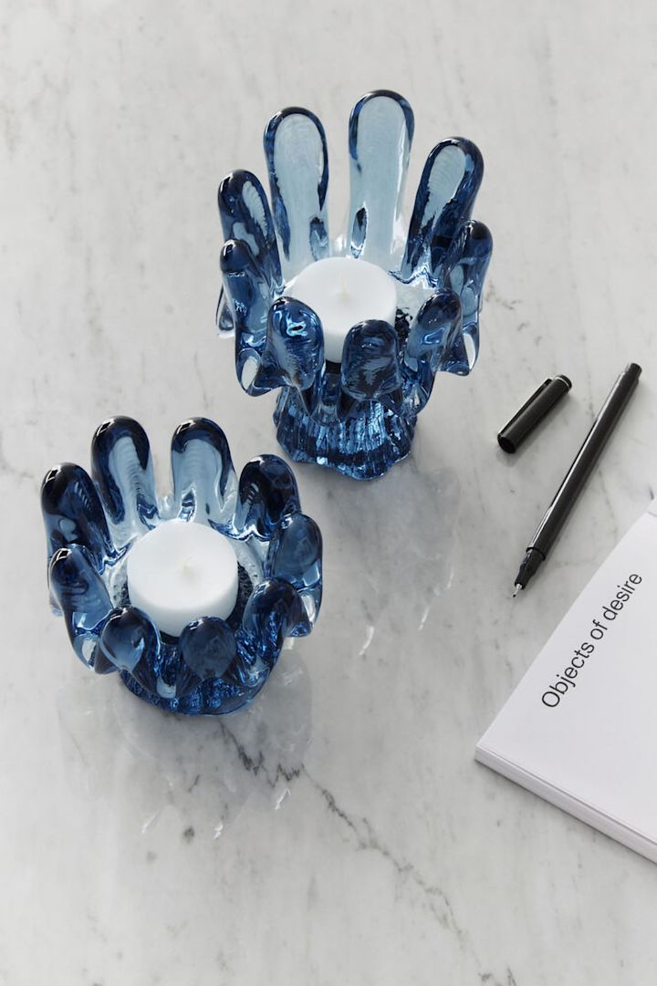 Tendances de la décoration intérieure 2025 : Deux bougeoirs bleus de la collection Solros de Kosta Boda sont posés sur une table claire.
