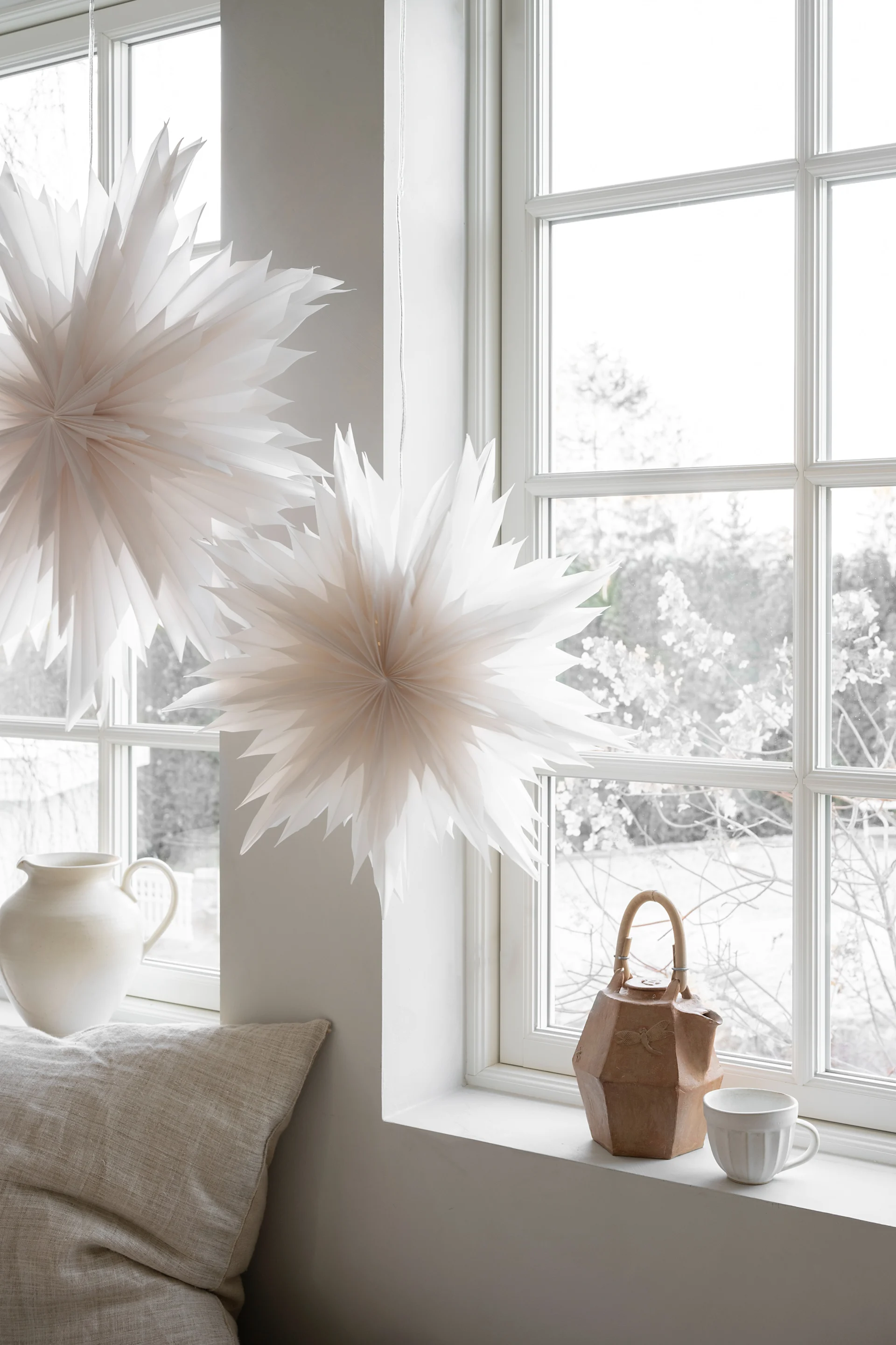 Étoiles en papier décoratives et ornements floraux superposés exposés parmi les arbres moussus de la forêt.