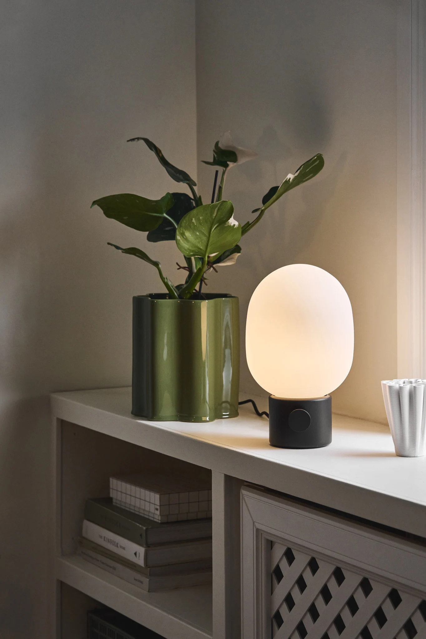 Lampes scandinaves : la lampe de table JWDA d'Audo Copenhagen est posée sur un rebord de fenêtre, à côté d'un pot de fleurs.