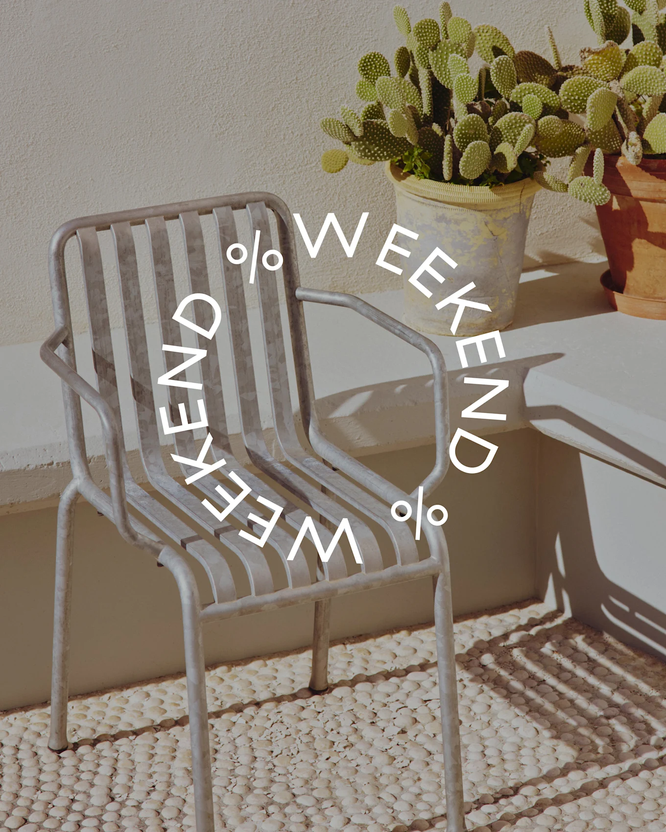 Chaise grise à lattes métalliques à côté d'un cactus en pot, avec le texte circulaire 'WEEKEND % WEEKEND %'.