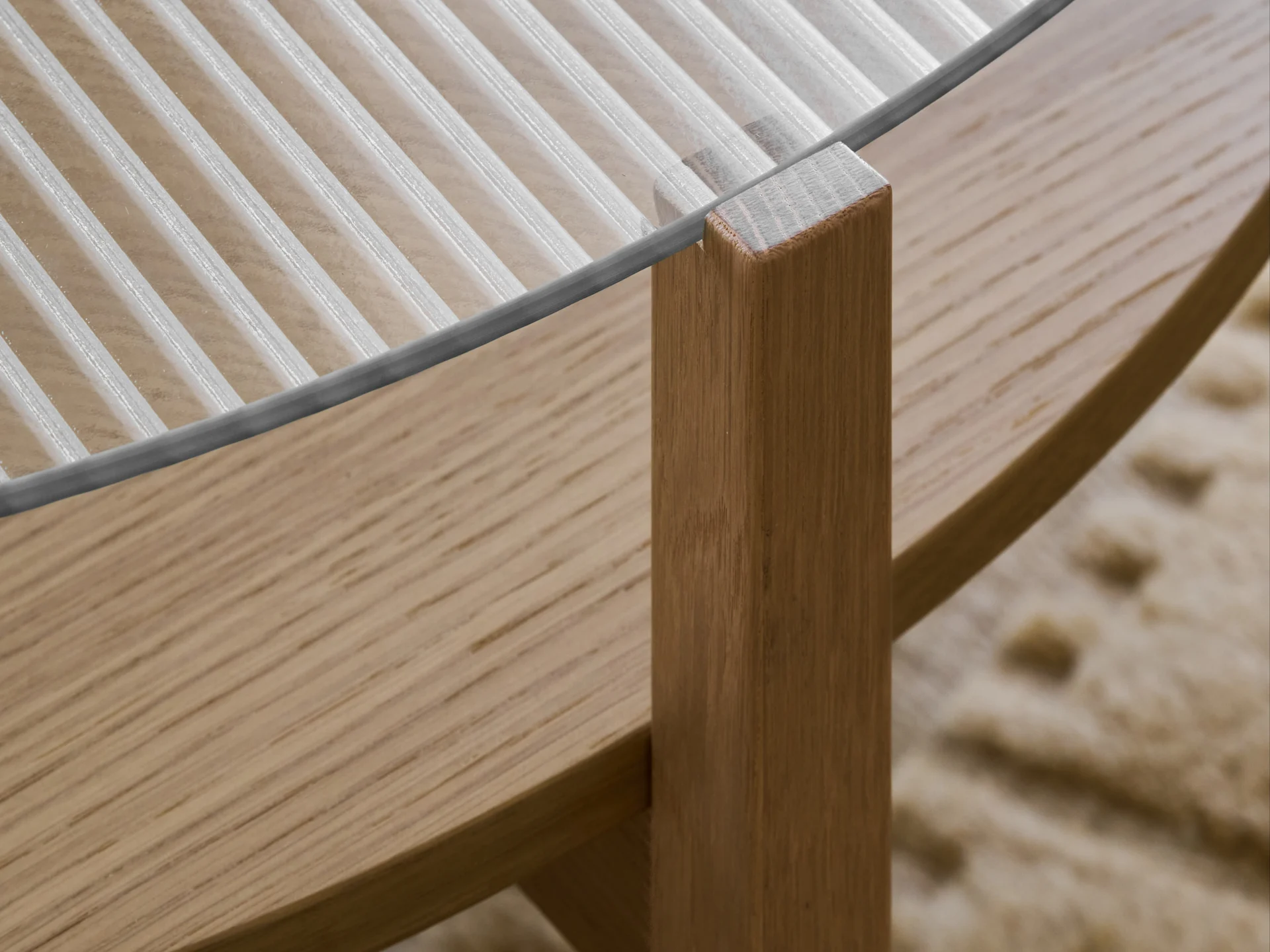 Gros plan d'une table avec un plateau en verre nervuré et un pied en bois marron clair.