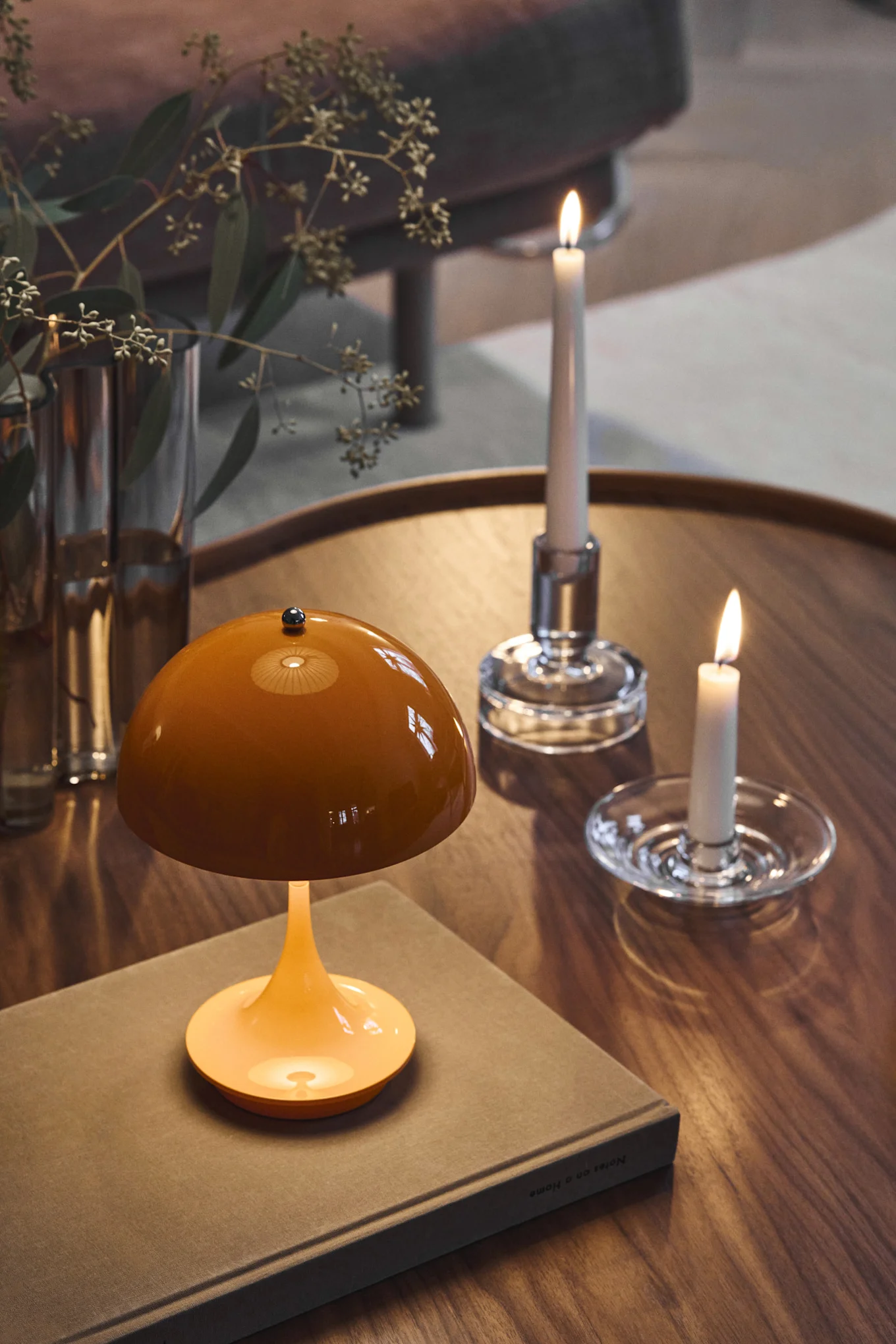 L'orange fait partie des couleurs tendance pour 2026. Il est présenté ici sous la forme d'une lampe Panthella posée sur une table basse à côté de bougeoirs en verre.
