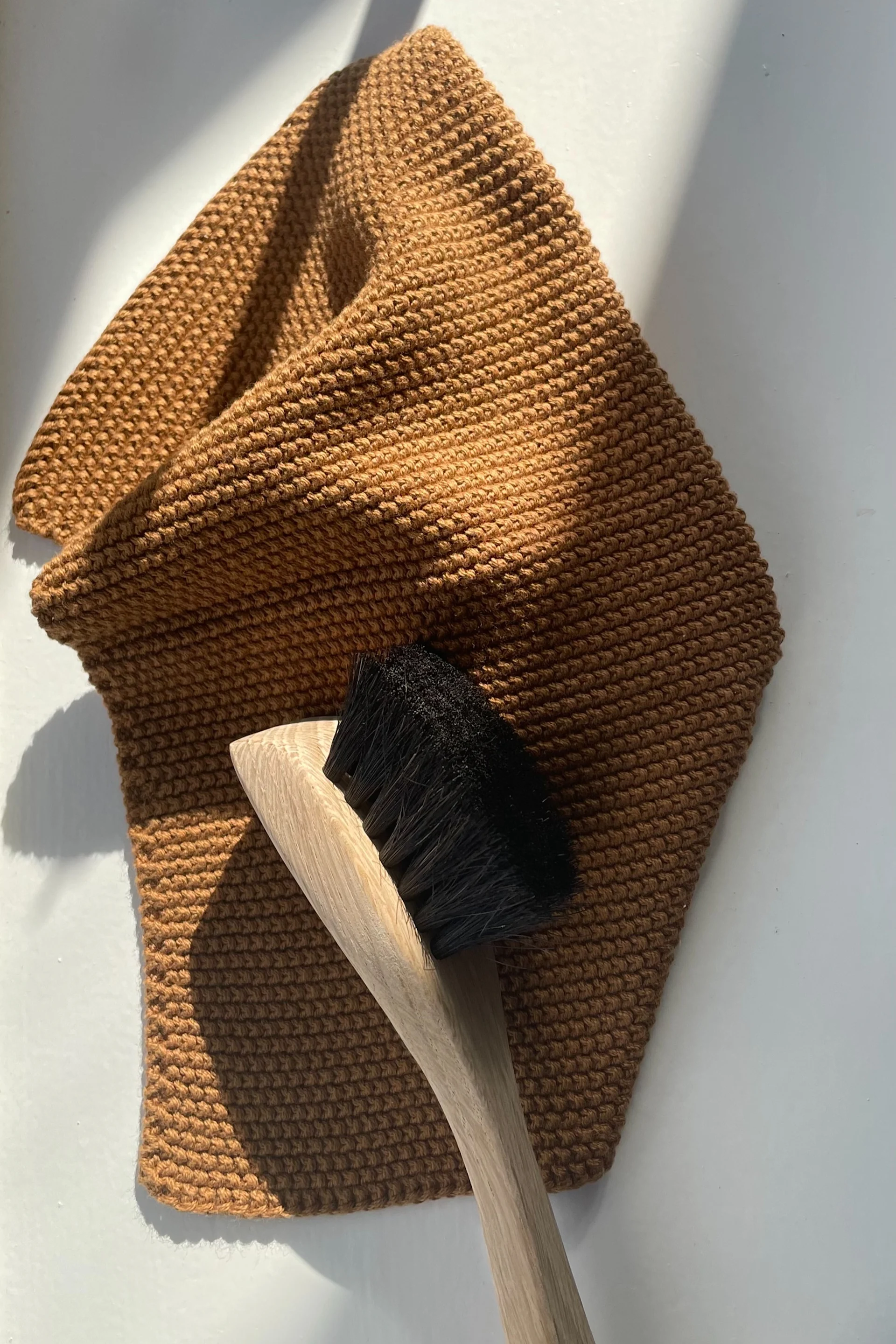 Nettoyez votre poêle à frire avec une brosse à vaisselle, qui est ici posée sur un chiffon à vaisselle marron, tous deux de Humdakin.