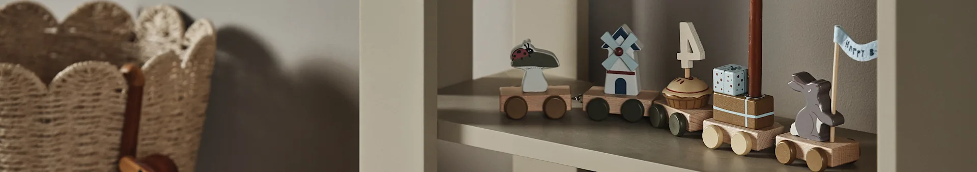 Un train jouet en bois sur une étagère, avec des wagons décorés d'une coccinelle, d'un moulin, d'un cupcake avec bougie '4', d'un cadeau et d'un lapin avec un drapeau "Happy B".
