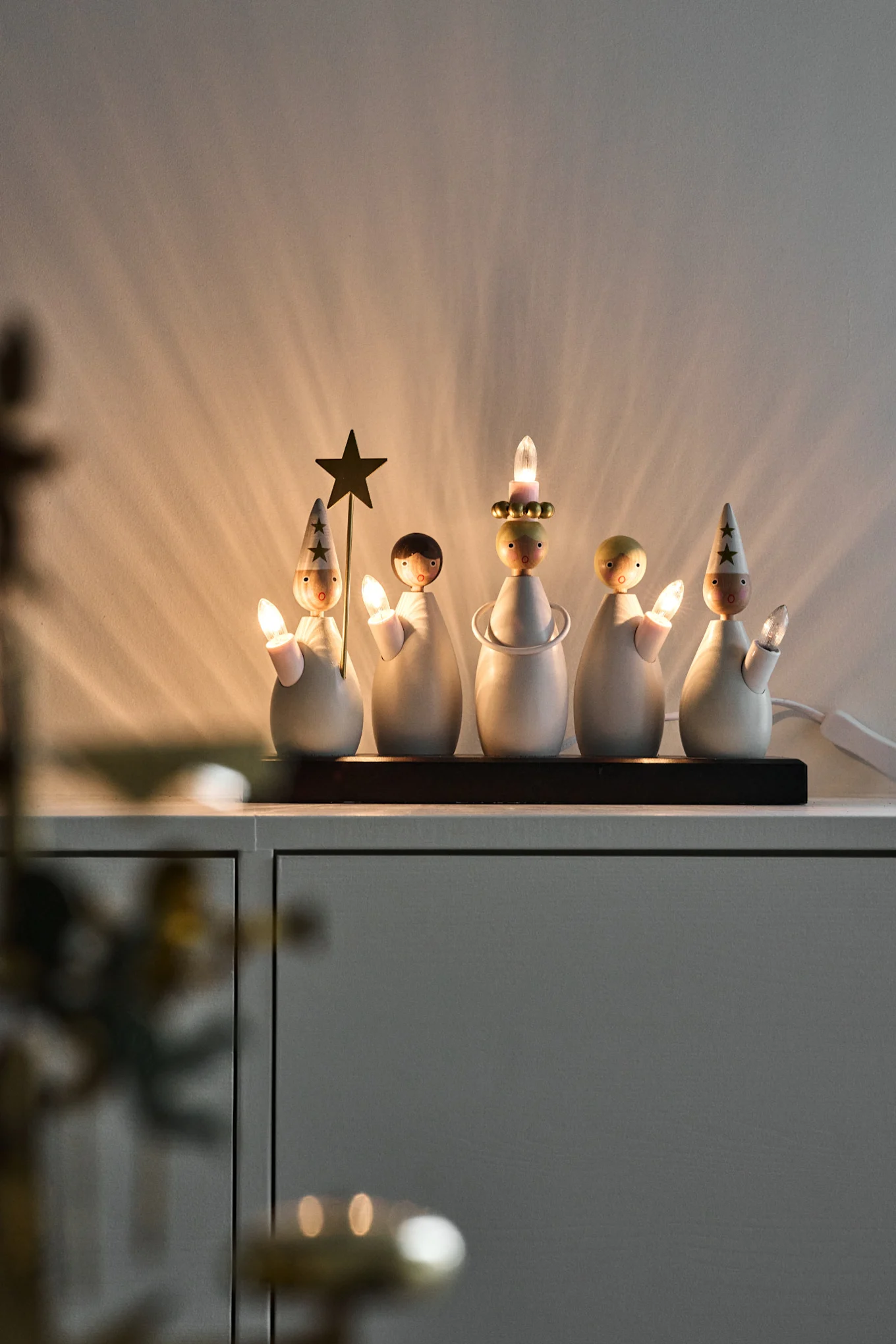 Un bougeoir de l'Avent représentant un cortège de Sainte-Lucie est posé sur une commode et brille de mille feux.