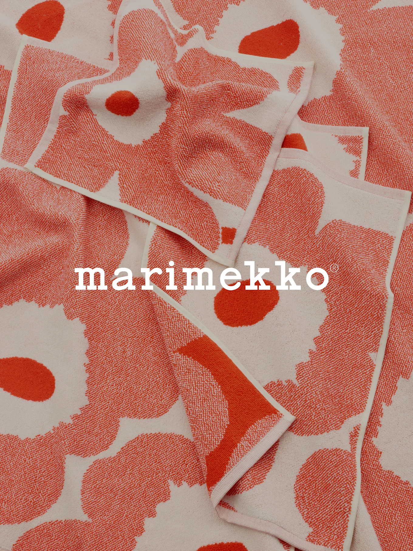 Serviettes pliées à motifs corail et blanc cassé avec le logo Marimekko.
