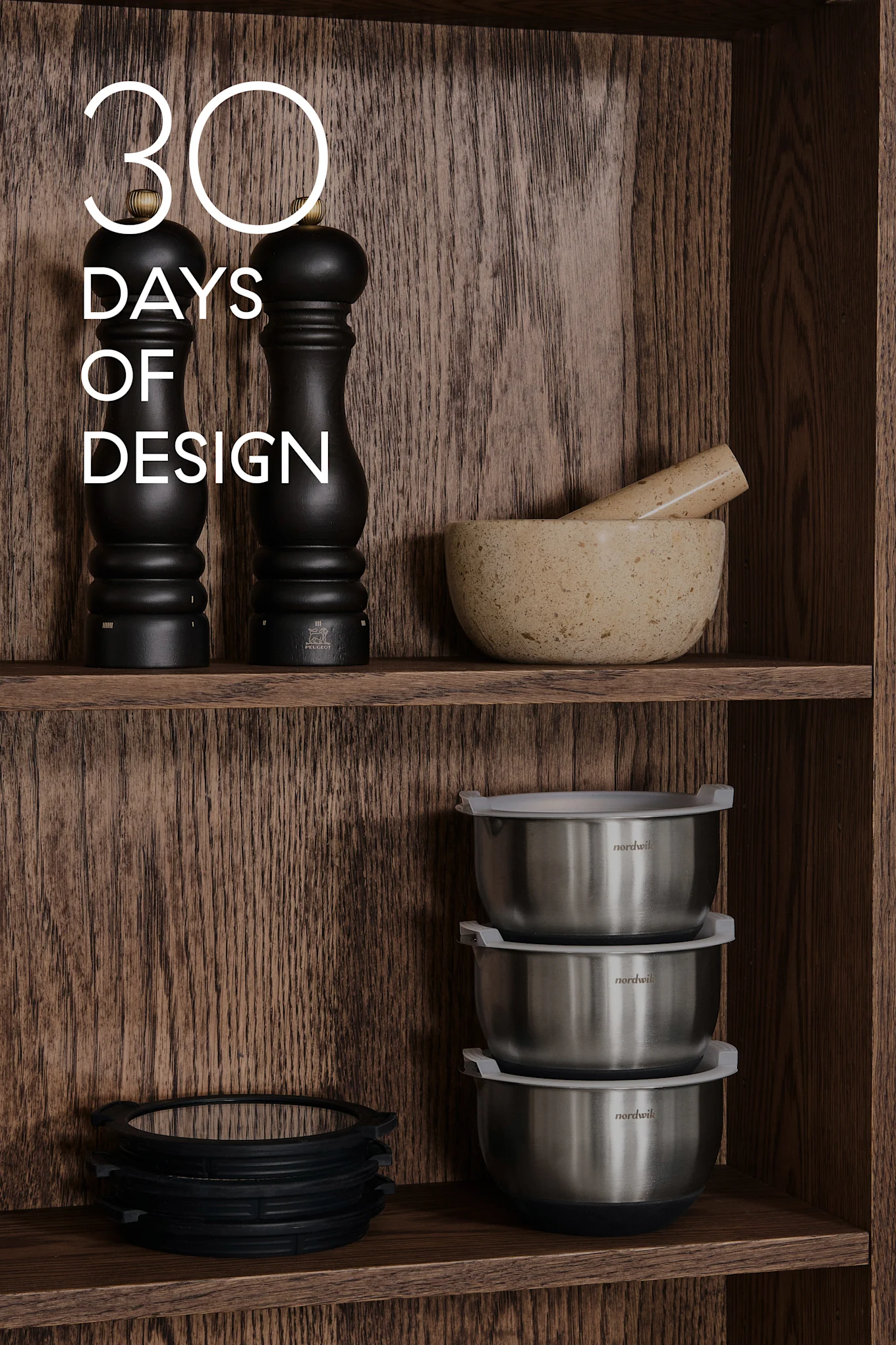 Étagères en bois avec ustensiles de cuisine: moulins noirs, mortier & pilon, bols en acier, anneaux en silicone. Texte: 30 DAYS OF DESIGN.