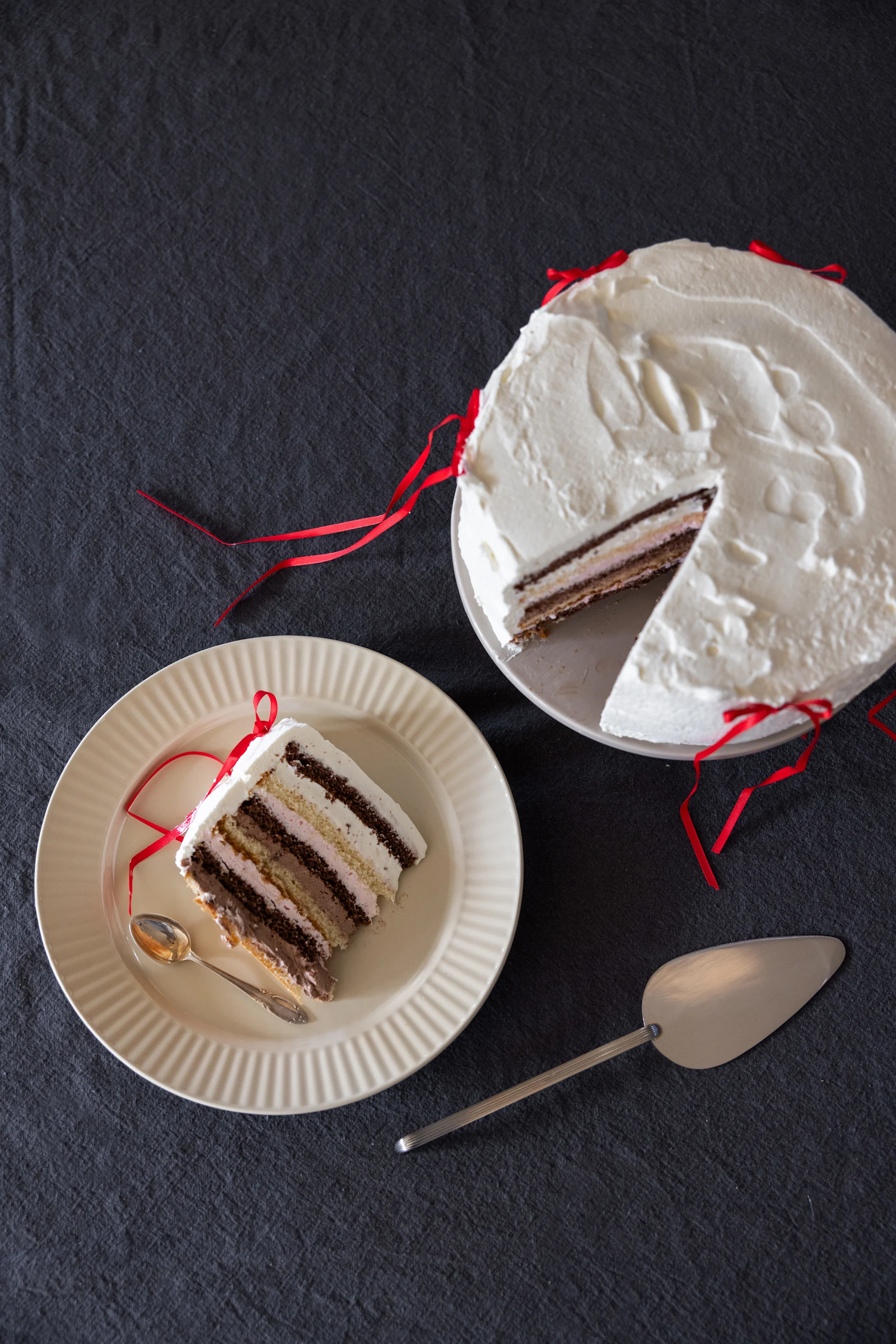 Un gâteau à la crème sur une assiette, à côté d'une part de gâteau sur une autre assiette de la collection Coffee & More de Sagaform, couleur beige.