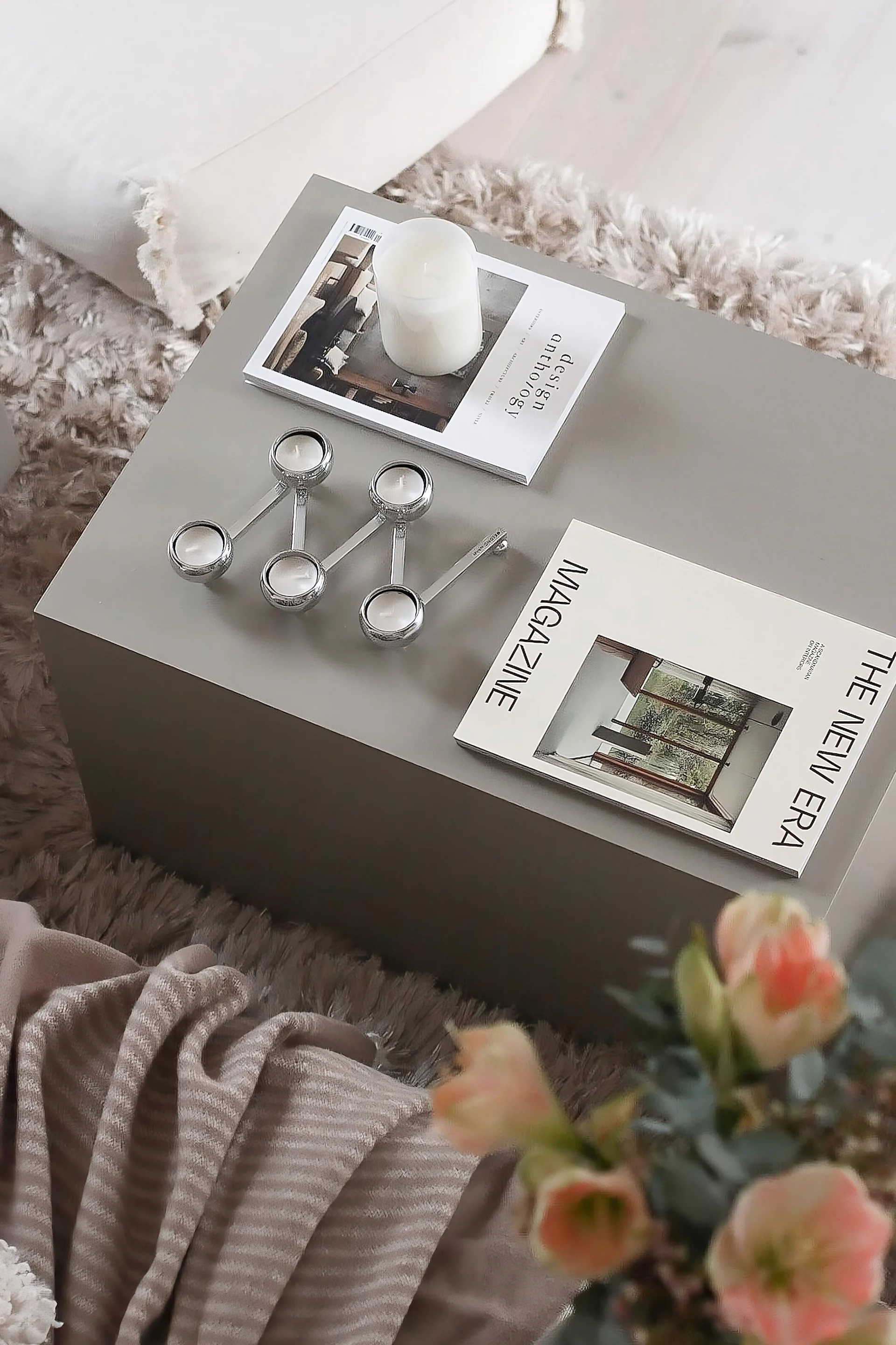 Une table basse rectangulaire décorée de magazines et du bougeoir Constella de Klong.