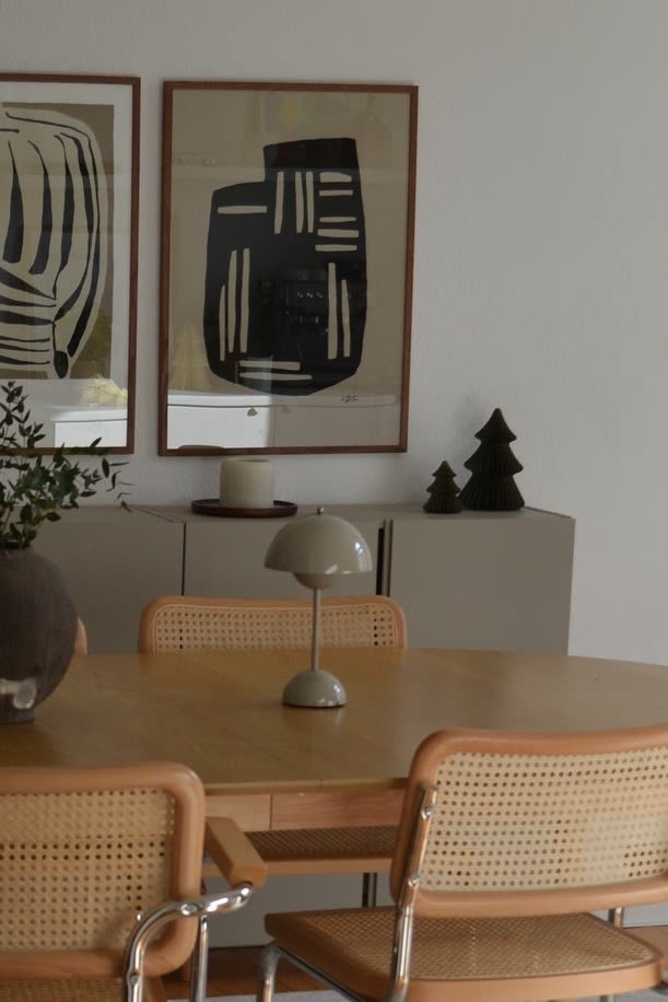 Le greige fait son retour dans les tendances de couleurs pour 2025. Ici, vous voyez la lampe sans fil Flowerpot VP9 de &Tradition sur une table de salle à manger en bois. 