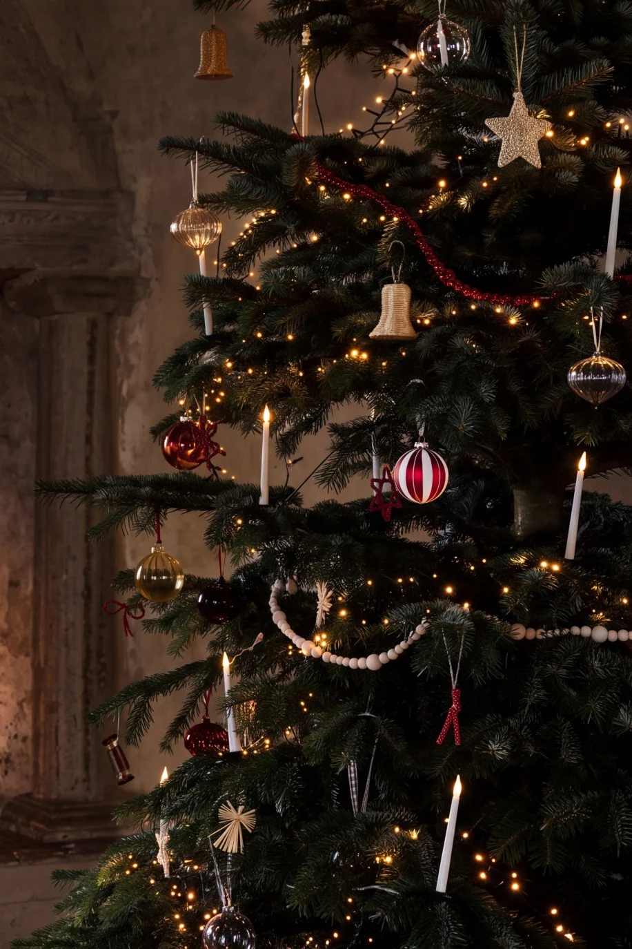 Un sapin de Noël décoré de lumières et de boules à côté d'une cheminée chaleureuse avec un feu ardent.
