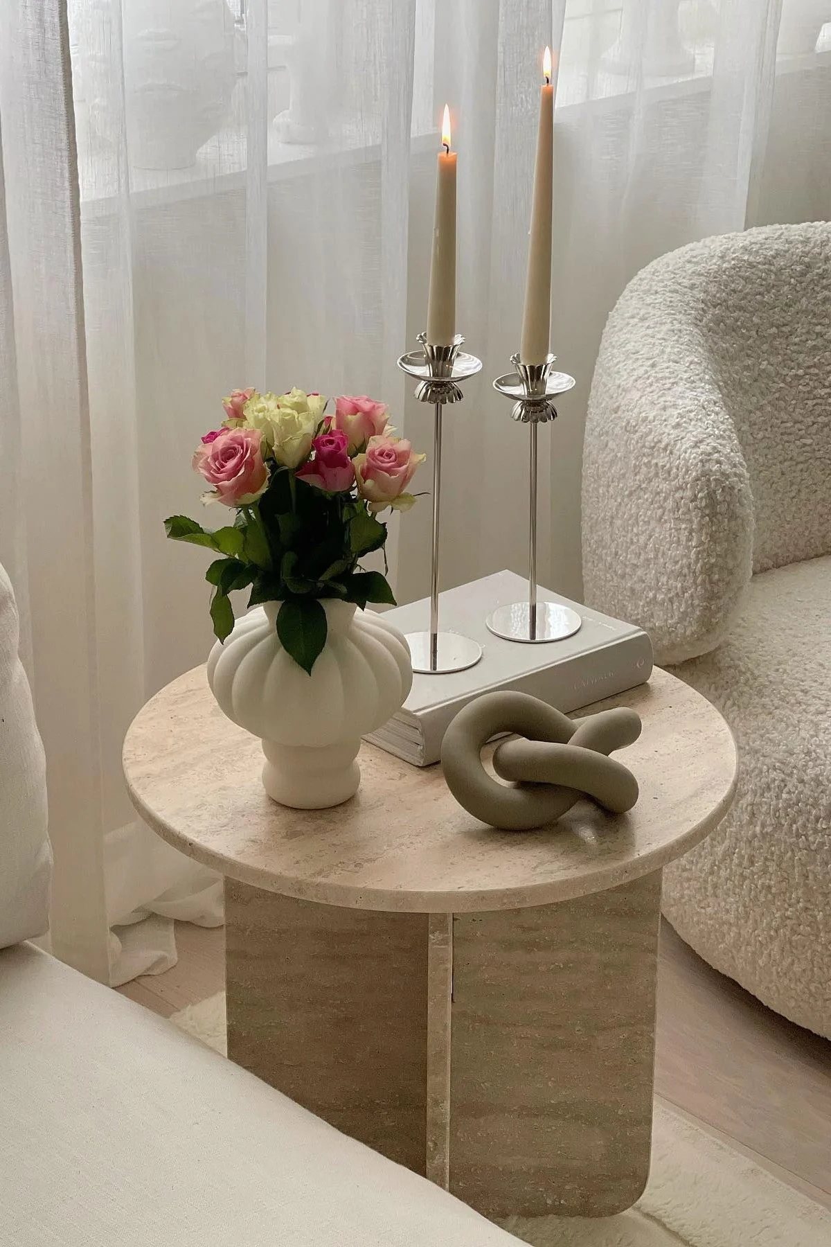 Une table basse décorée avec un vase Louise Roe Balloon, un livre, deux bougeoirs et la décoration Knot de Cooee Design.