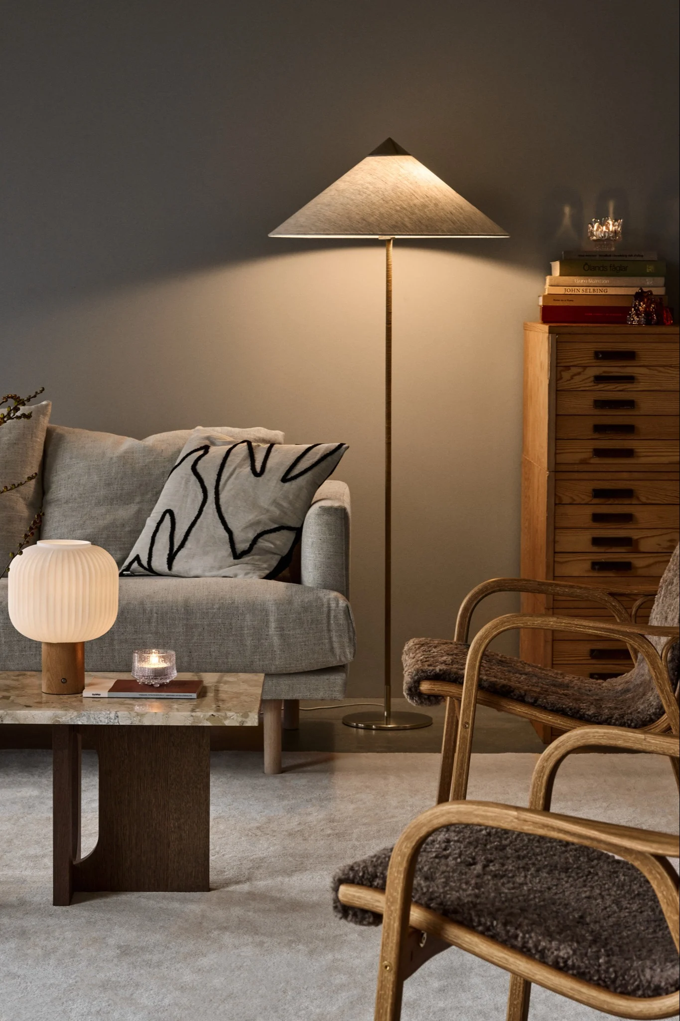 Un salon avec une lampe portable Fair de Scandi Living posée sur une table, accompagnée de deux fauteuils. 