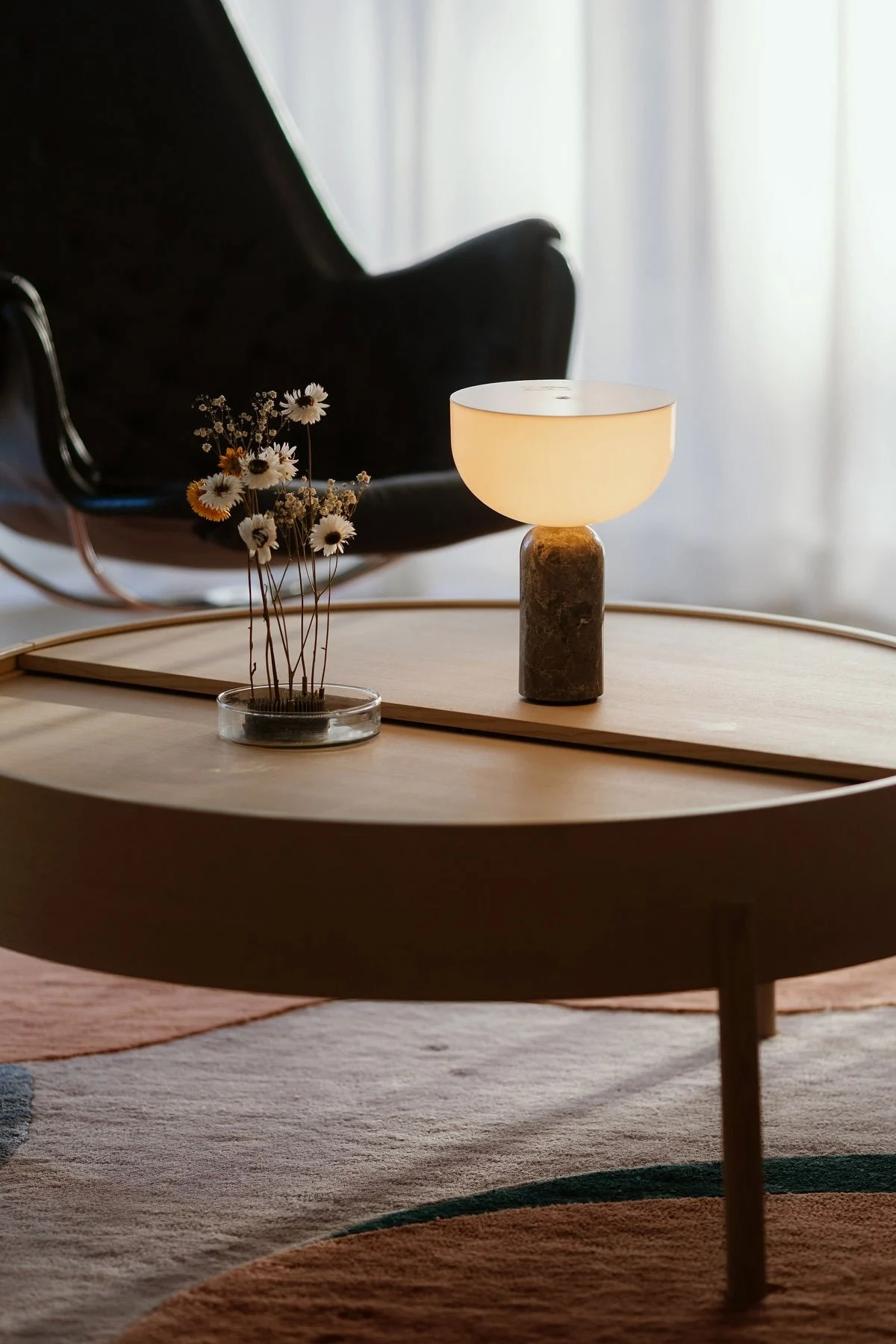 La table basse Arc de Woud est décorée d'une lampe de table Kizu de New Works et d'un hérisson à fleurs Garden Glory.