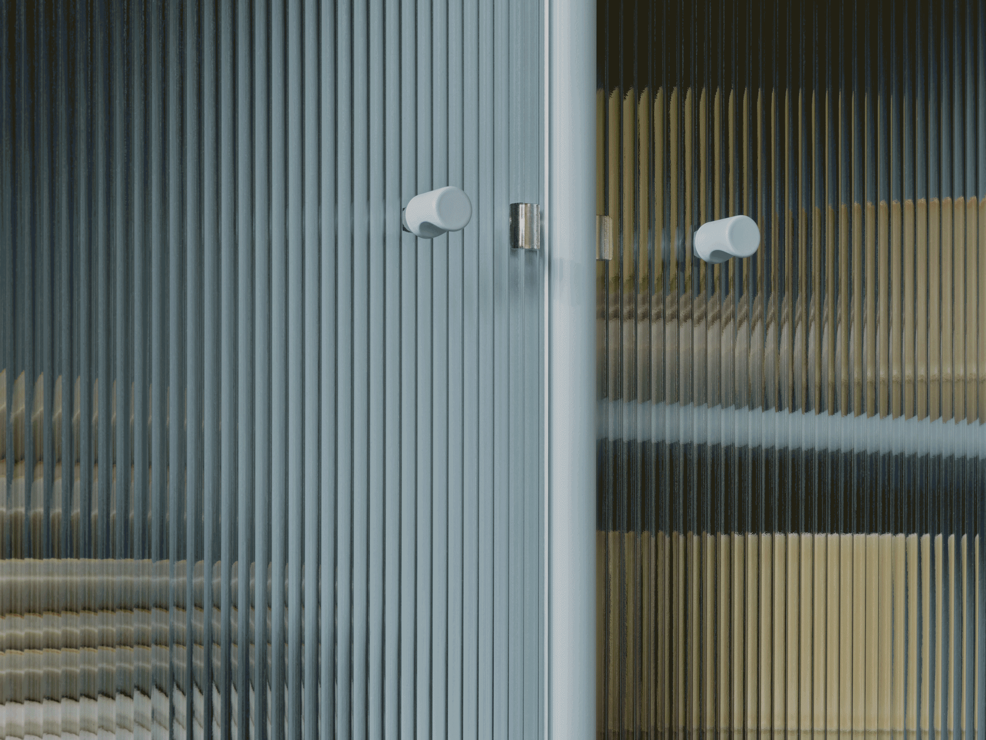 Gros plan d'une porte en verre cannelé avec deux poignées rondes claires, montrant des couleurs déformées par la texture.