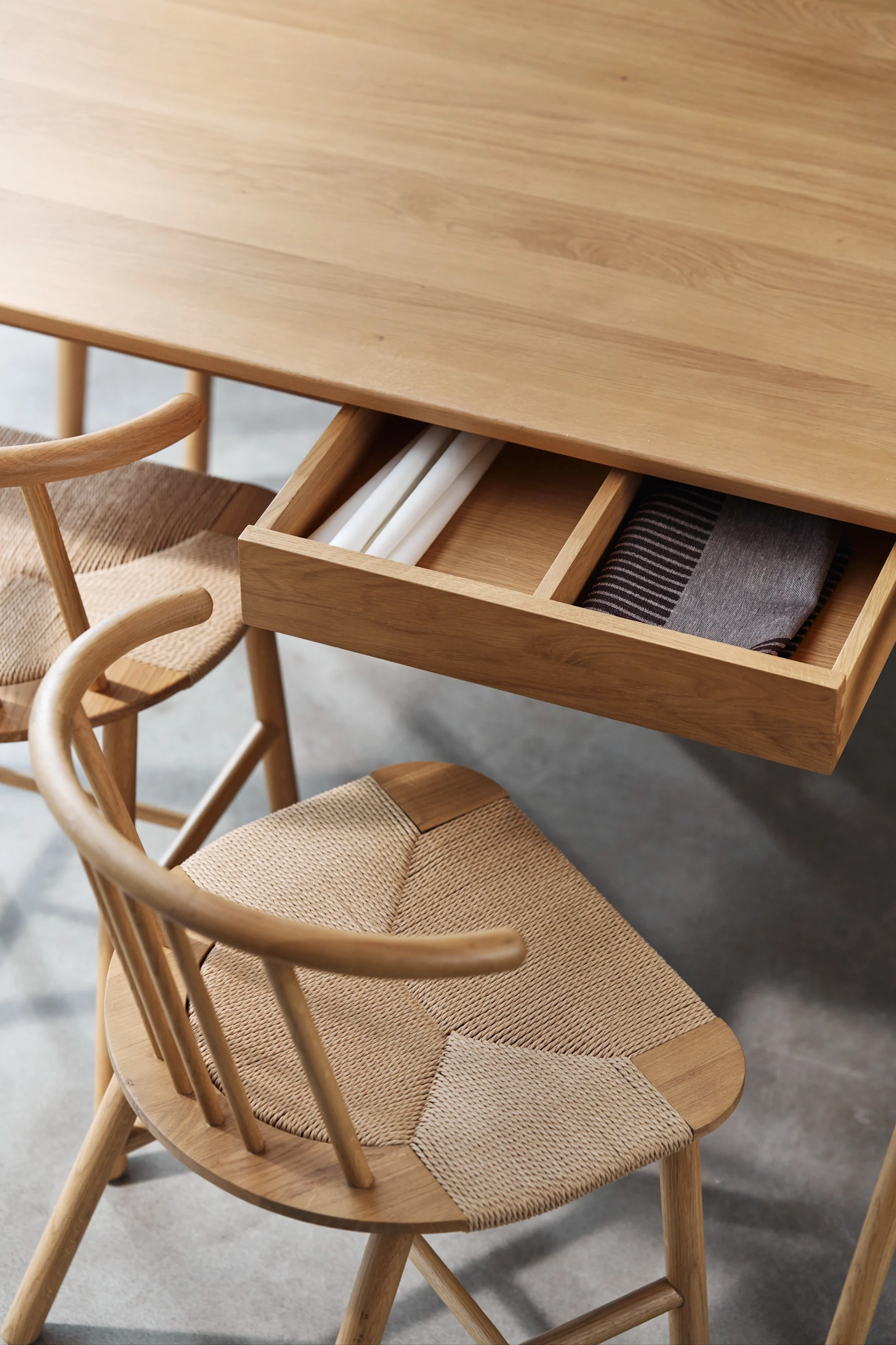 Tendances 2025 de la décoration d'intérieur scandinave - meubles multifonctionnels. Ici, une table en chêne de NJRD avec un tiroir coulissant pour ranger les détails.