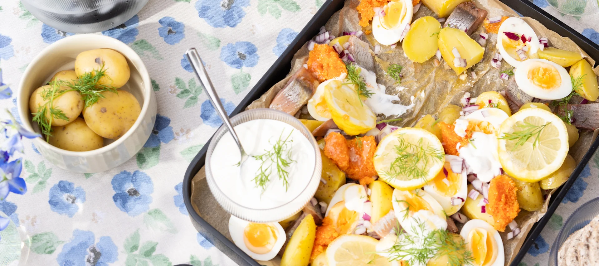 Recettes d'été : Une salade de pommes de terre suédoise avec des œufs et du matjes sur une table, à côté de pommes de terre.