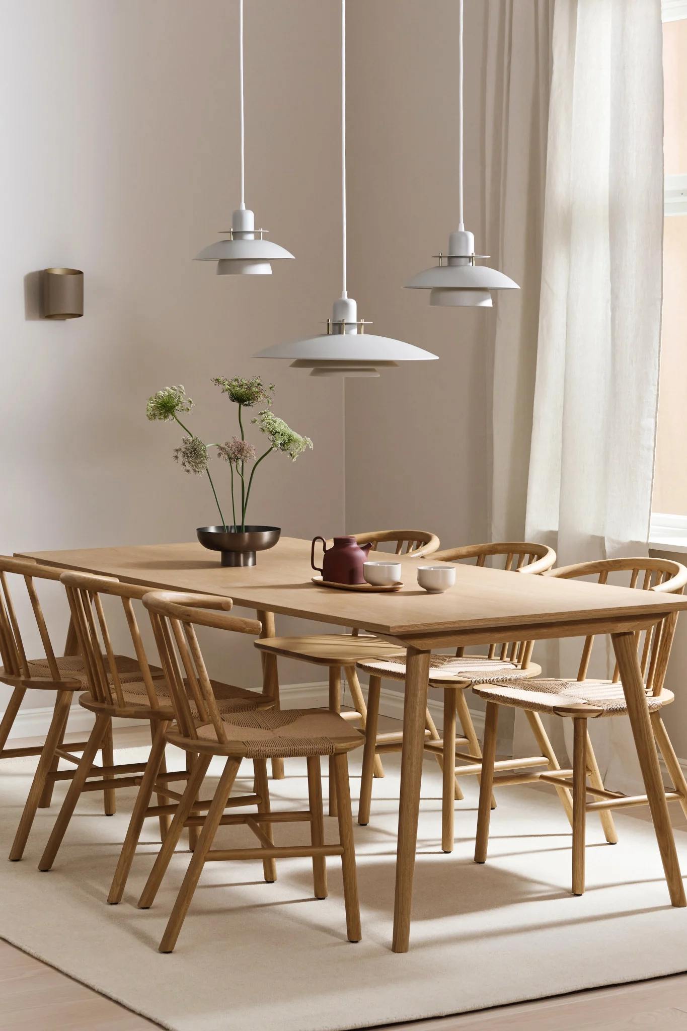 Voici des idées d'éclairage de salle à manger pour une longue table. La lampe Picasso est suspendue en rangée de trois et la lampe Sinne est accrochée au mur. 