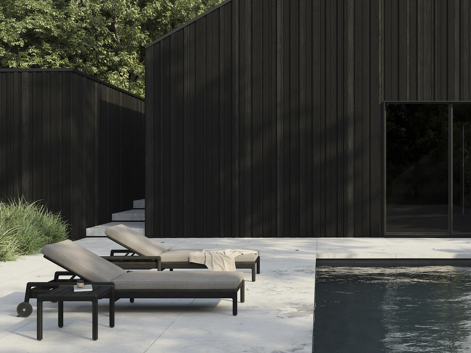 Deux transats foncés avec des coussins clairs sur une terrasse près d'une piscine, avec des bâtiments modernes en bois foncé en arrière-plan.