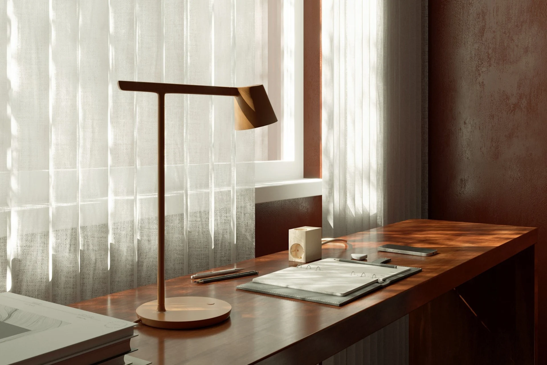 Un espace de travail avec une lampe de bureau moderne, un bloc-notes et un smartphone sur un bureau en bois près d'une fenêtre avec des rideaux transparents.