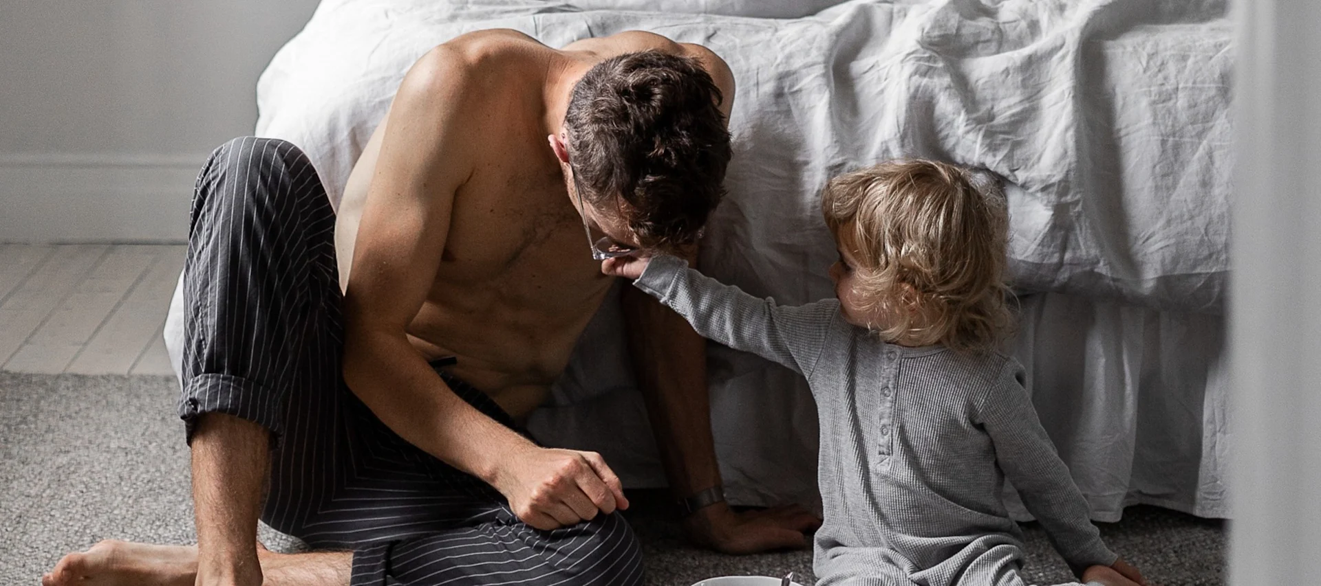 Cadeaux pour la fête des pères : vous voyez ici un homme assis devant un lit avec un petit enfant.