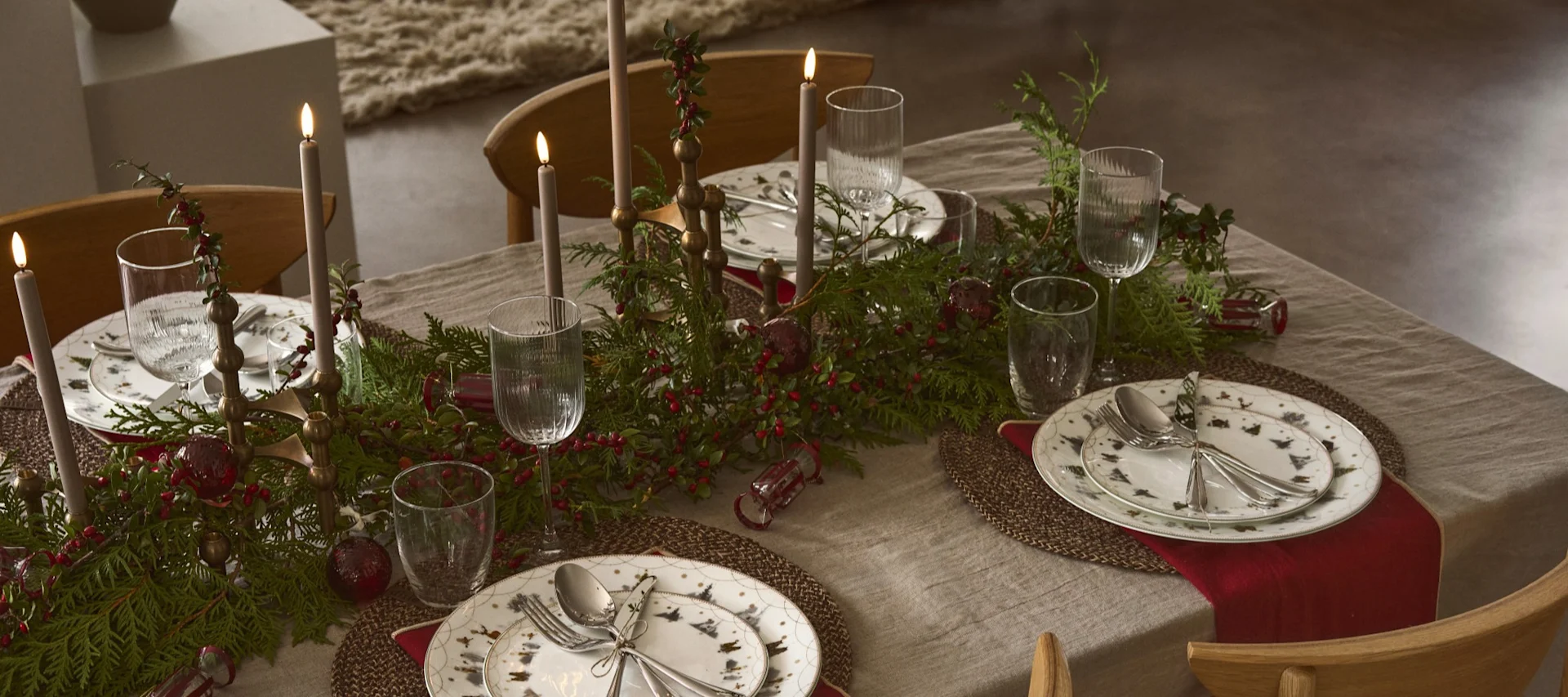 Une table décorée de branches de sapin et de nappes rouges qui répand l'ambiance de Noël.