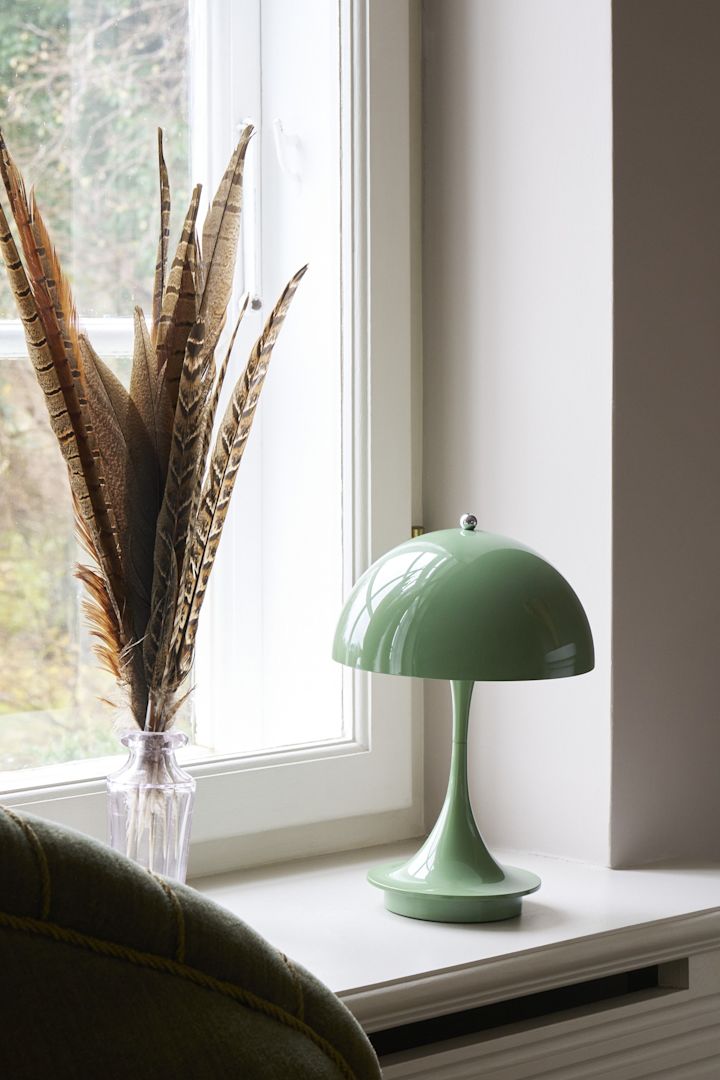 La couleur sauge est l'une des tendances de la décoration intérieure de l'automne 2025. Ici, la lampe de table Panthella de Louis Poulsen, de couleur sauge, est posée sur un rebord de fenêtre.
