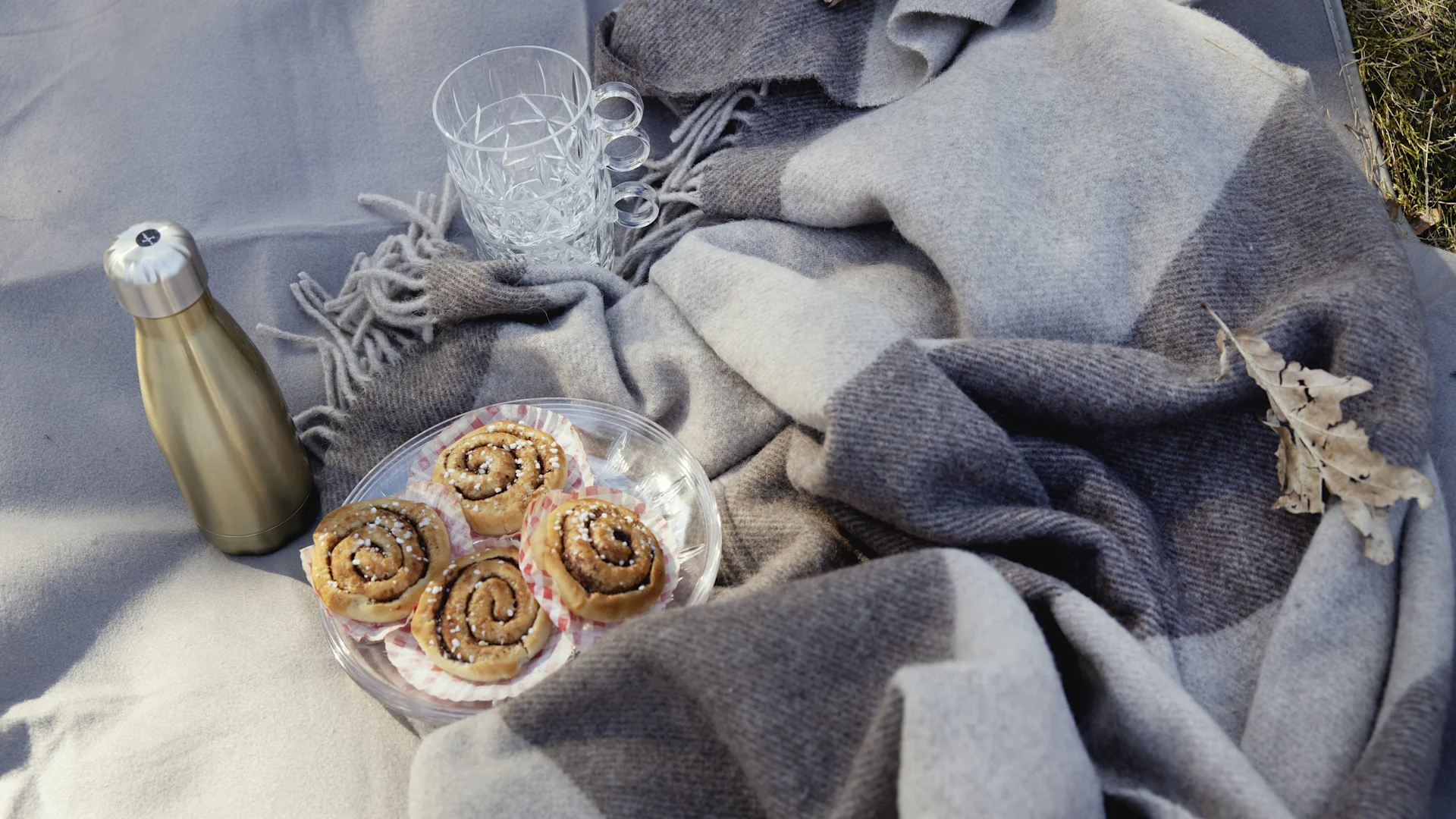 Sur une couverture de pique-nique se trouvent une assiette de brioches à la cannelle, un thermos et des verres de pique-nique Sagaform : des cadeaux parfaits pour la Saint-Valentin.