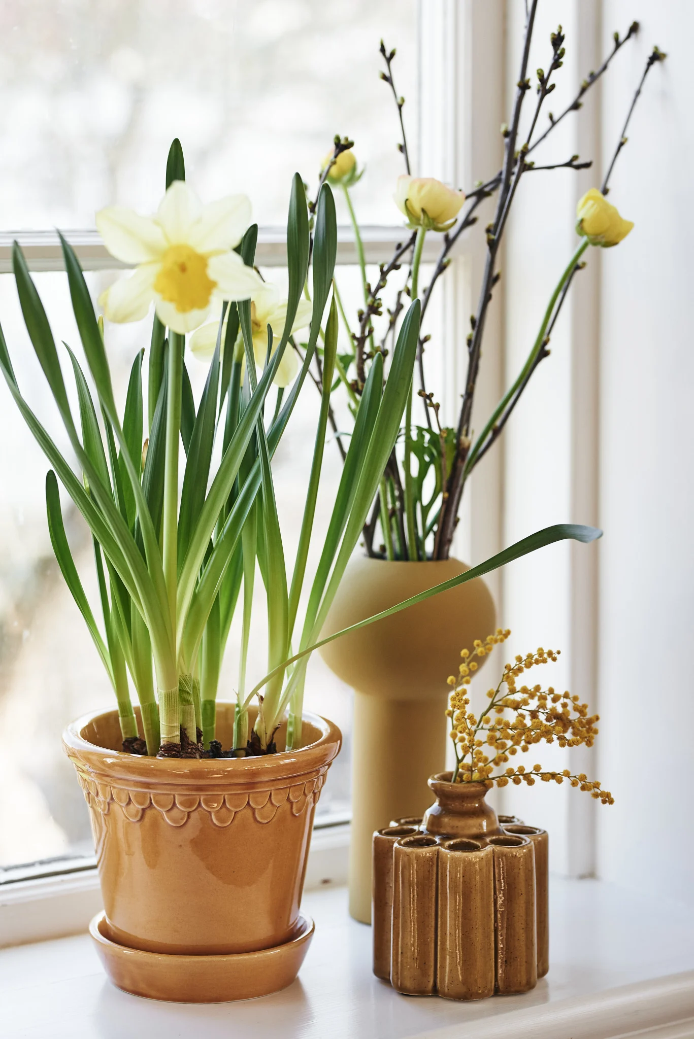 Décoration de Pâques : Ici, vous voyez des fleurs printanières dans le vase Pillar de Cooee Design et le pot de fleurs jaune Kopenhagen de Bergs Potter.