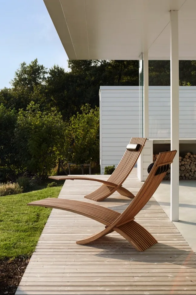 Tendances meubles de jardin 2025 : les chaises longues Nozib de Skargaarden existent avec leur forme organique et se trouvent ici sur une terrasse avec vue sur la verdure.