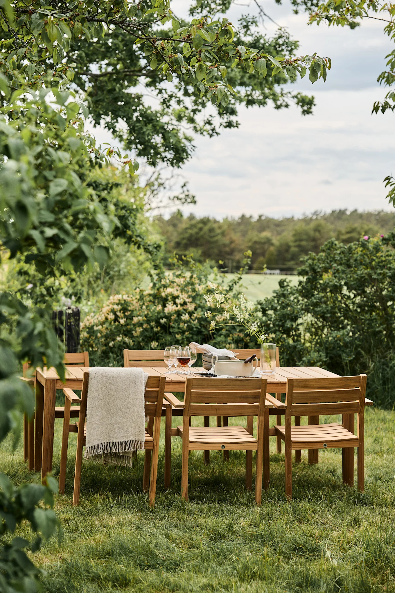 Tendances des meubles de jardin en 2025 : les chaises Sköndal de 1898 sont placées autour d'une table dans un jardin très vert.