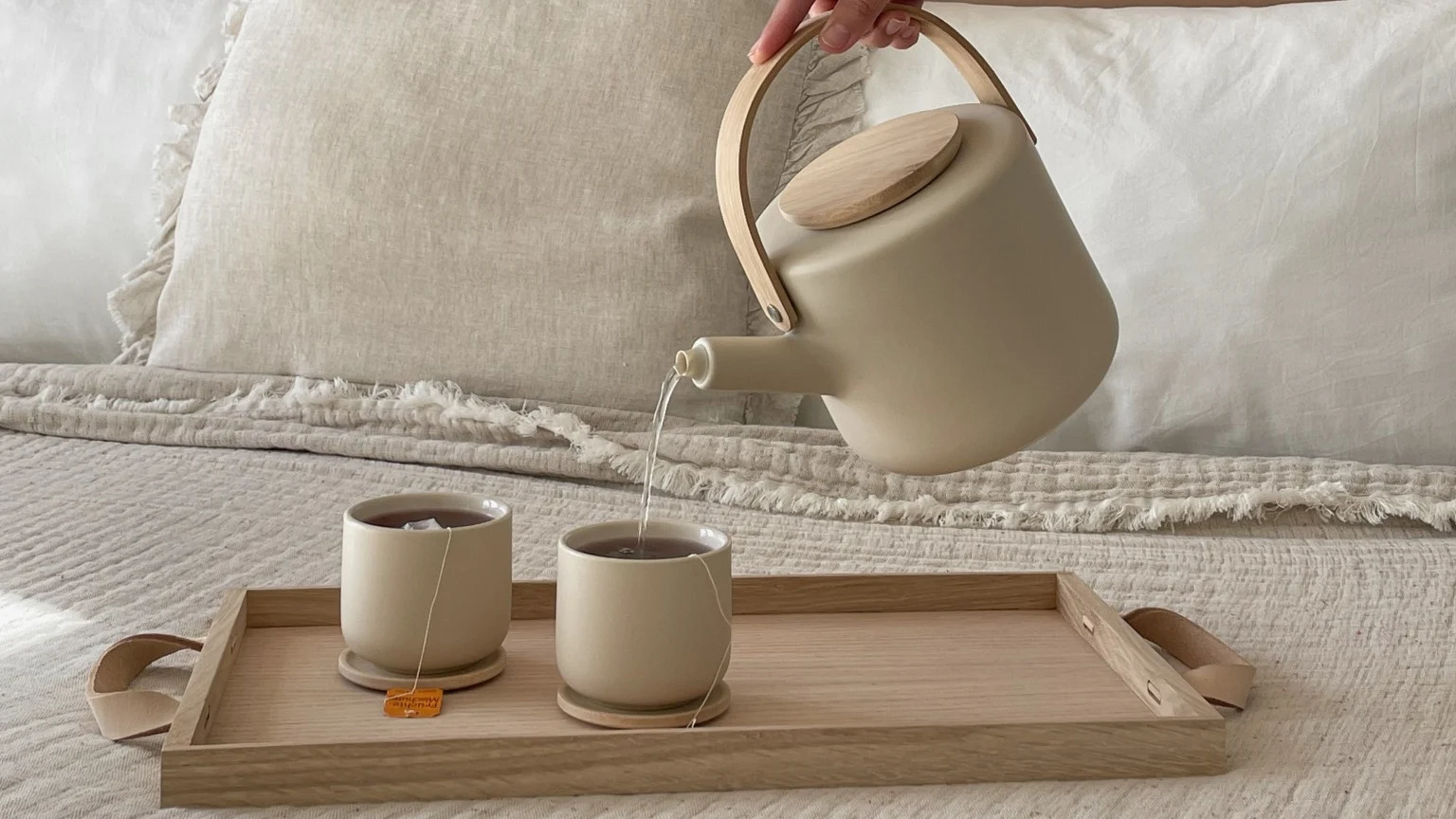 Le Feng Shui est également synonyme de calme et de détente. Ici, @our_home_living verse du thé à l'aide de la théière Theo de Stelton dans deux tasses Theo posées sur un plateau sur un lit.