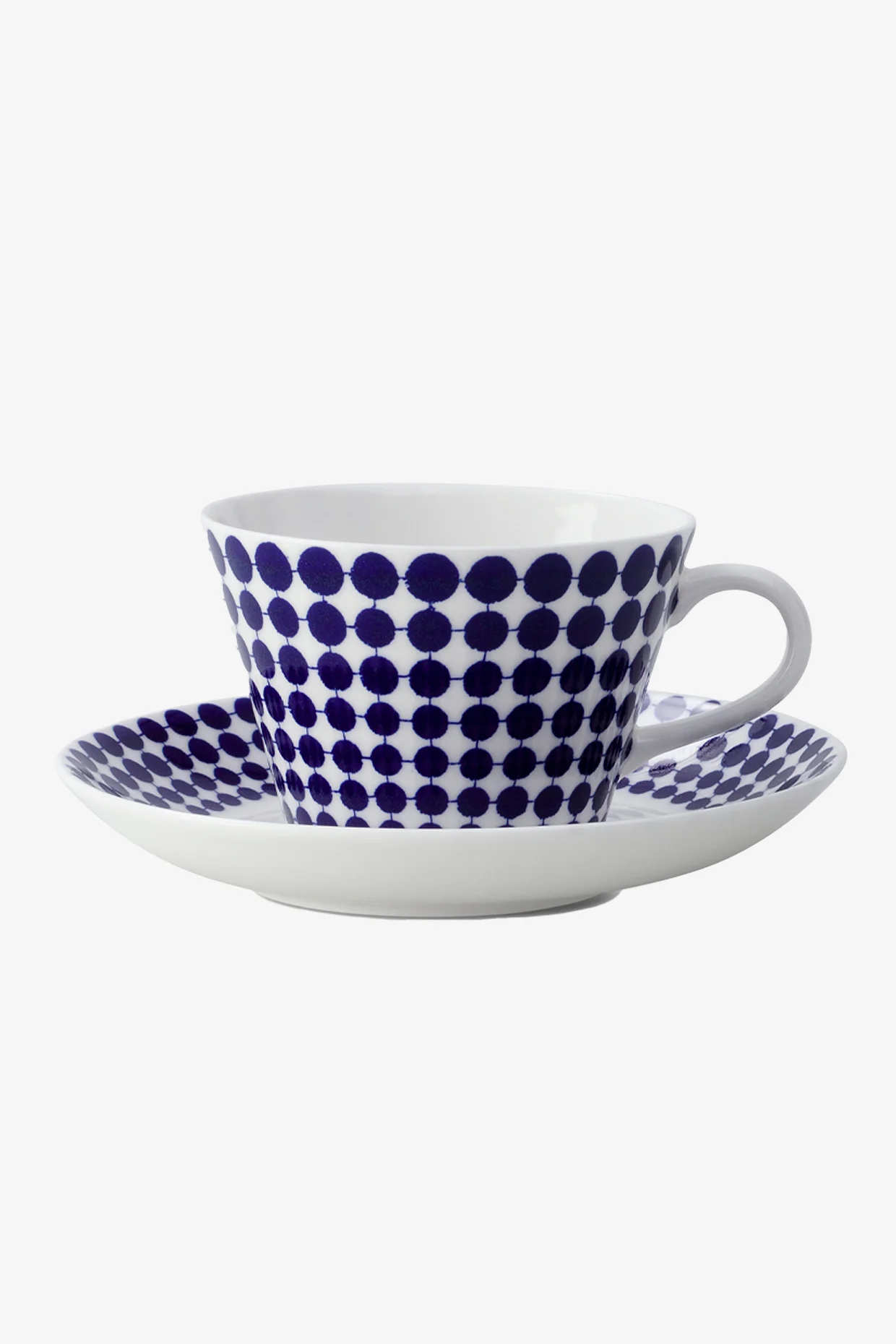 Tasse à thé et soucoupe blanches avec un motif à pois bleus.