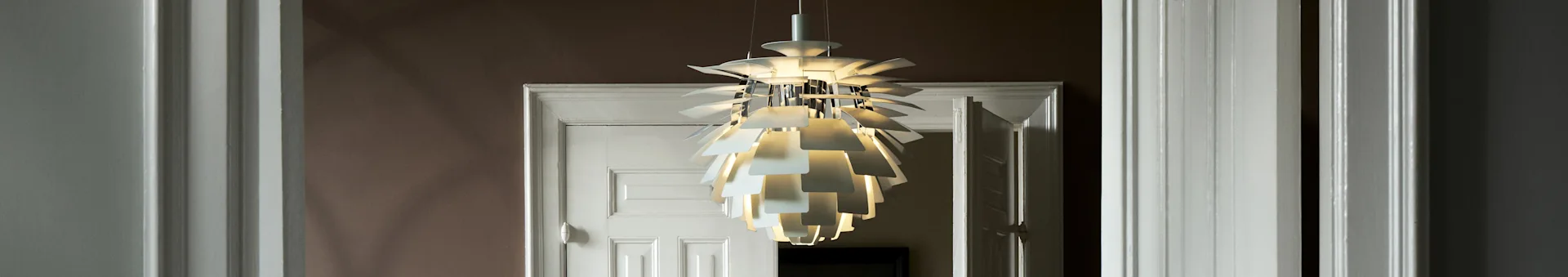 Une suspension blanche et sculpturale à plusieurs couches illumine une embrasure de porte.