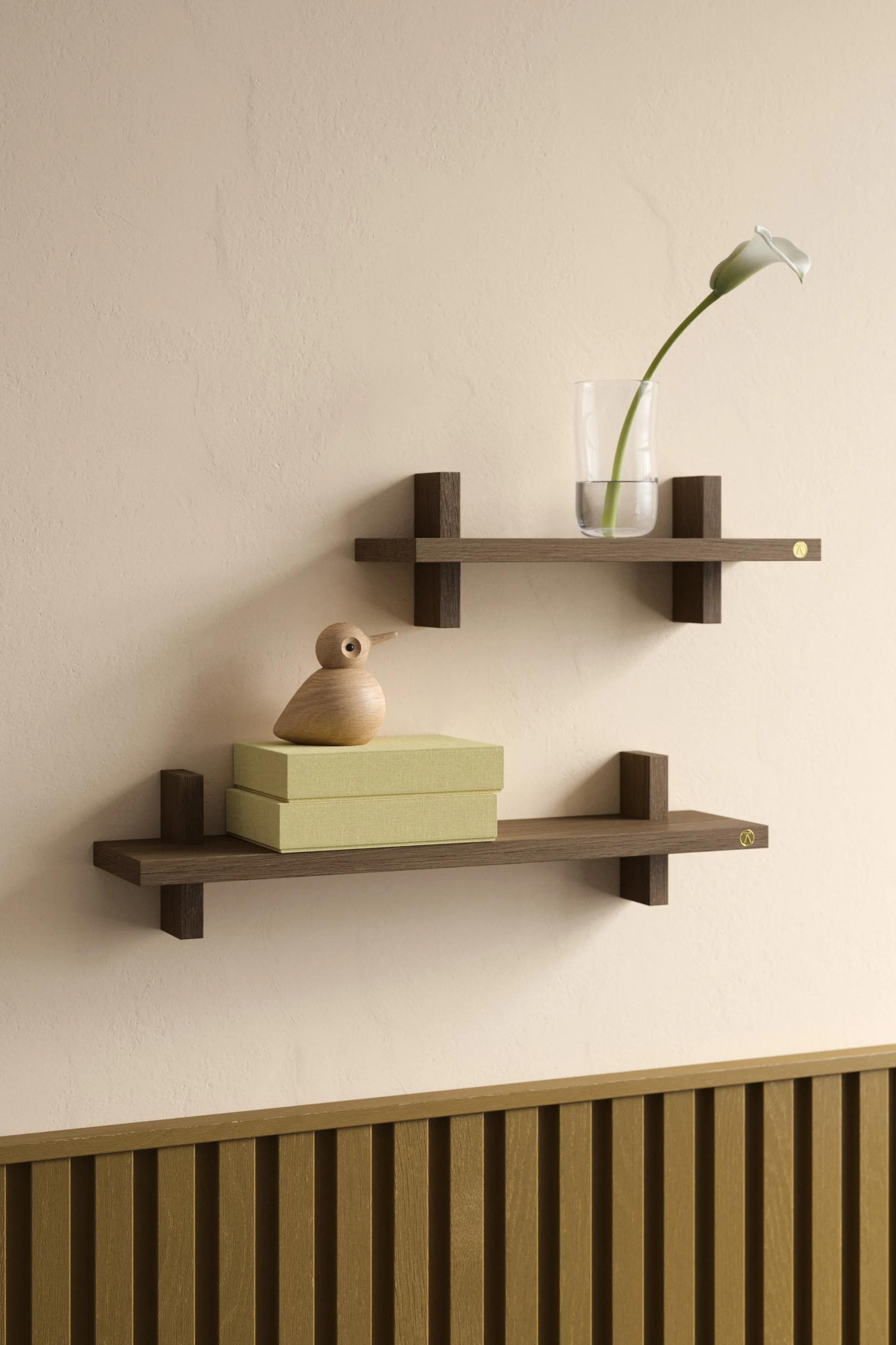 Deux étagères flottantes en bois foncé sur un mur beige, l'une avec un vase et un lys, l'autre avec des boîtes vertes et un oiseau en bois.