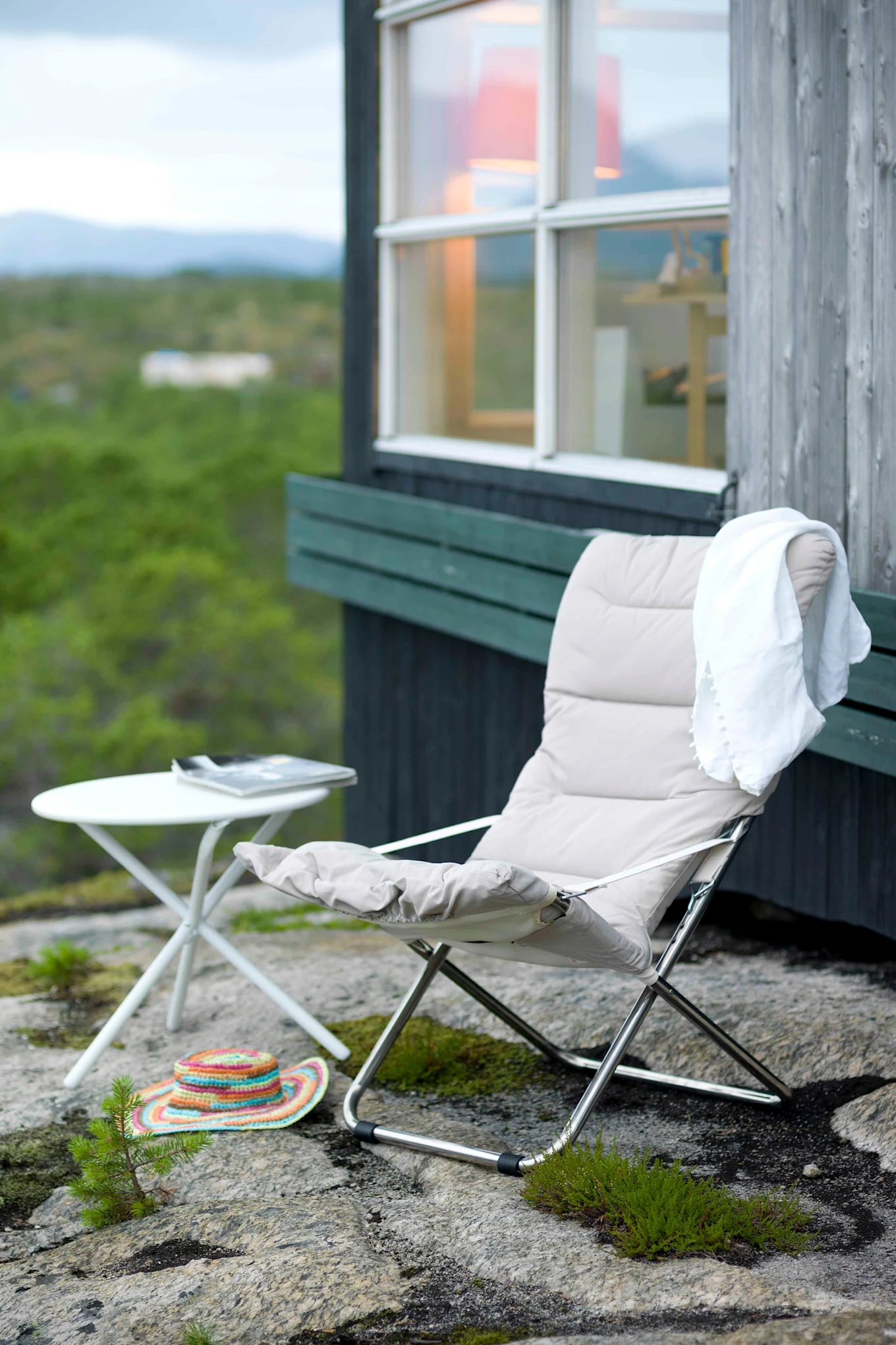 La chaise longue Fiesta Soft de Fiam est installée sur une terrasse avec une forêt en dessous. Grâce à sa facilité de pliage, elle fait partie des meubles de jardin tendance de cette année.