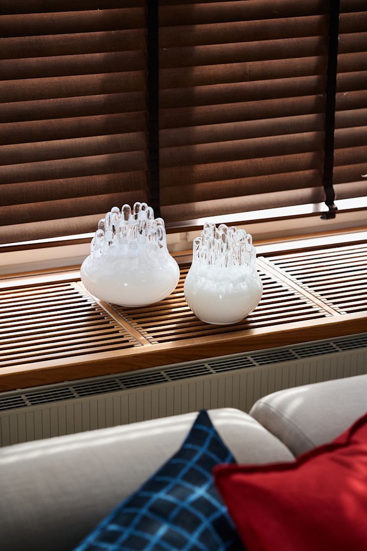 Tendances design de l'automne 2025 : Deux bougeoirs Polar blancs de Kosta Boda sont posés sur un rebord de fenêtre.
