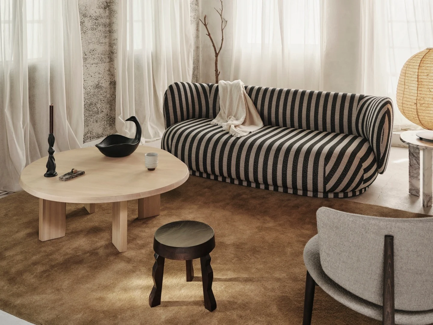 Salon douillet avec un canapé rayé noir et écru, une table basse en bois clair et un plafond rustique à poutres apparentes.