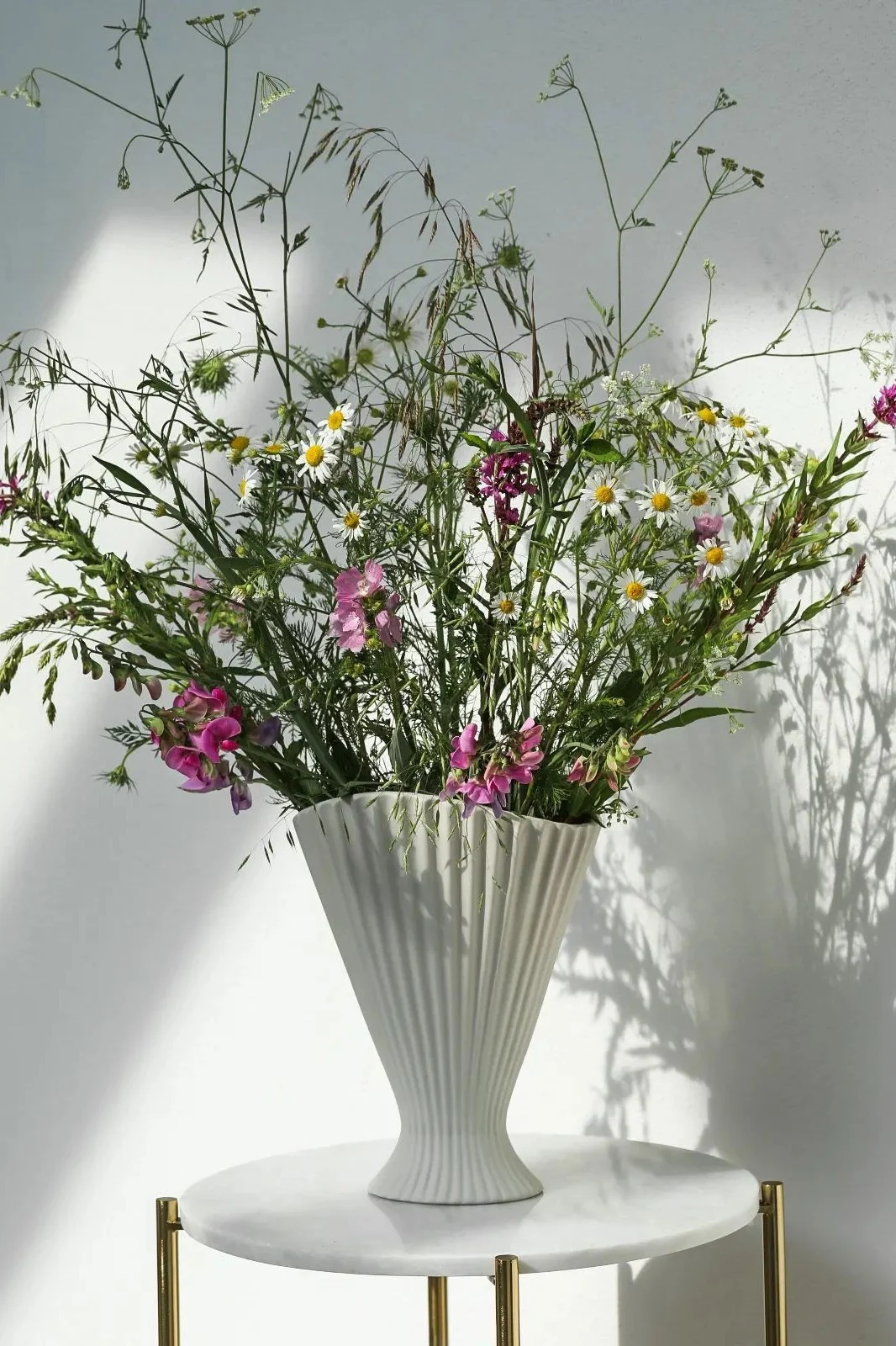 Sur la table d'appoint de @houseandermosel trône le grand vase Fountain de Ferm Living, rempli de nombreuses fleurs printanières.