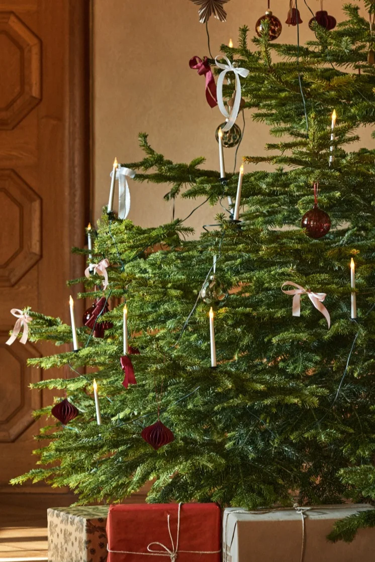 Les idées traditionnelles de décoration de l'arbre de Noël comprennent des éléments tels que les bougies électriques et les boucles que vous voyez ici sur un arbre décoré en rouge, blanc et or. 